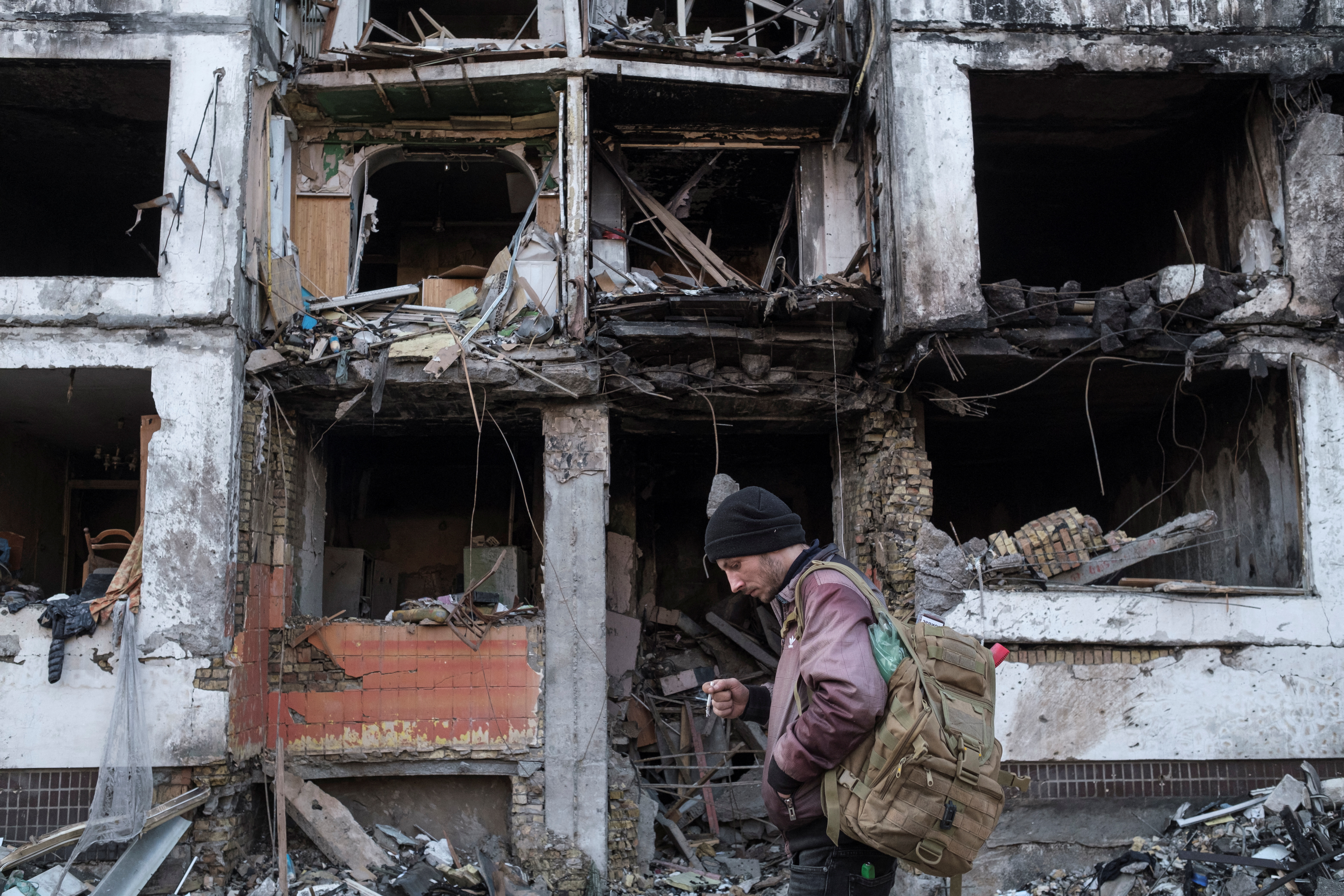 A man stands in front of a residential building that was recently hit by shelling in Kyiv