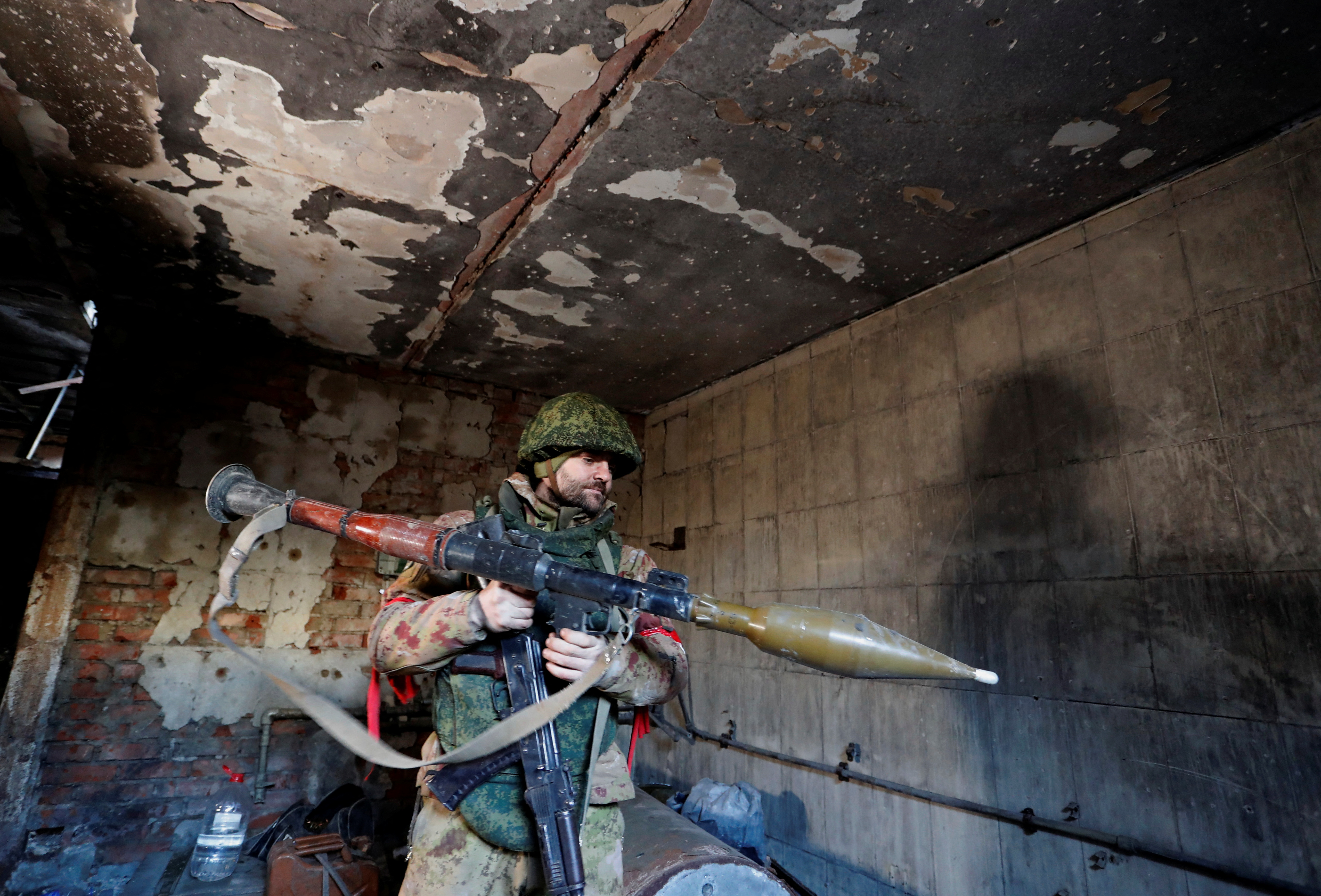 A service member of pro-Russian troops checks weapons inside a building, which according to the military, was previously a fighting position of Ukrainian armed forces, in Marinka