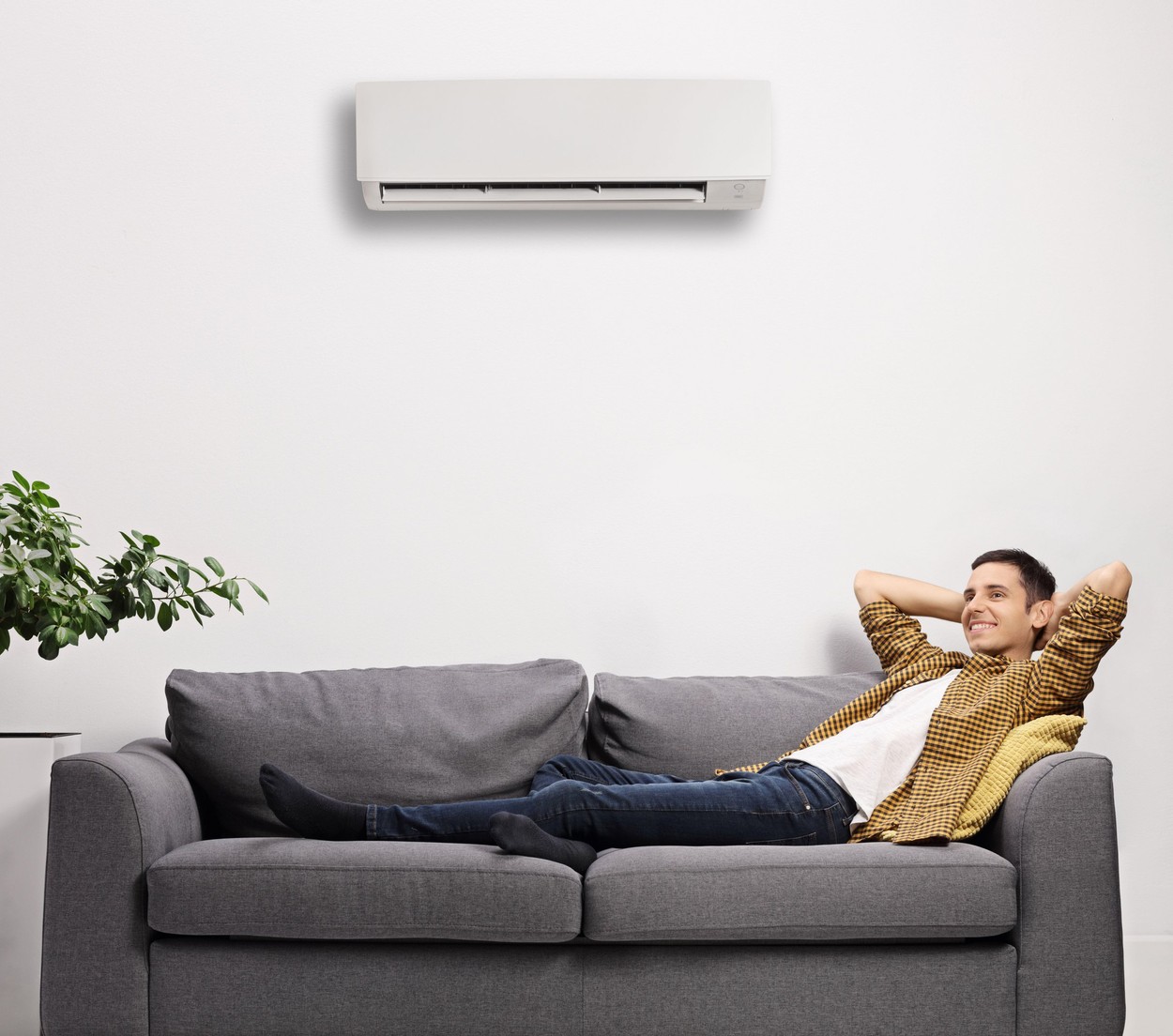 Man enjoying on a sofa with air conditioning unit on the wall isolated on white background