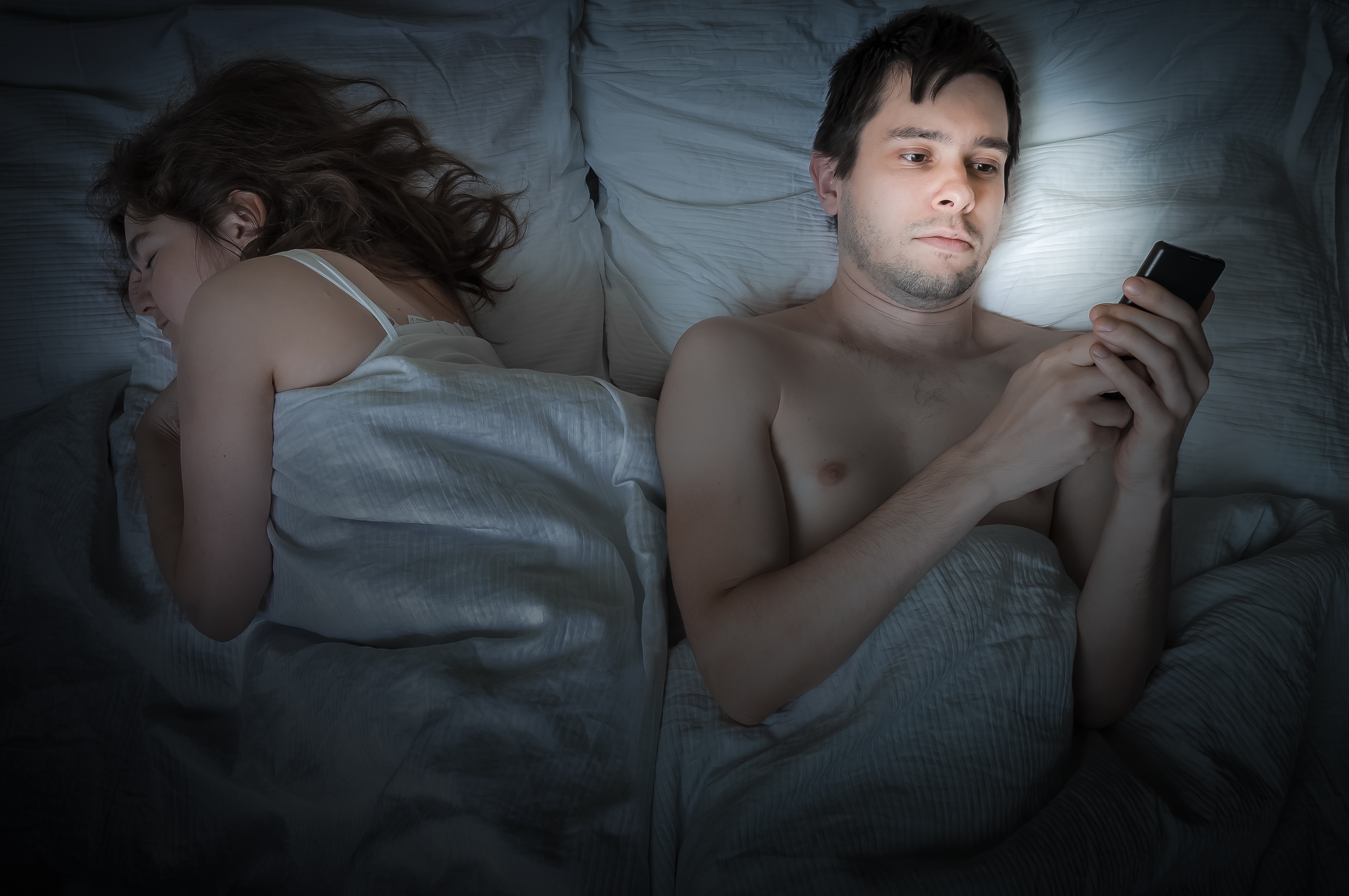 Young,Man,Is,Lying,With,Girlfriend,In,Bed,And,Texting