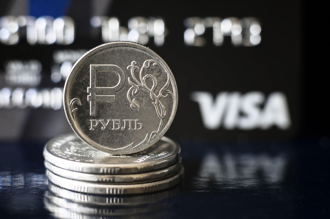 Moscow - March 6, 2022: Ruble coin and Visa credit card, Russian money is under pressure from sanctions. Concept of currency, cancelled transactions a