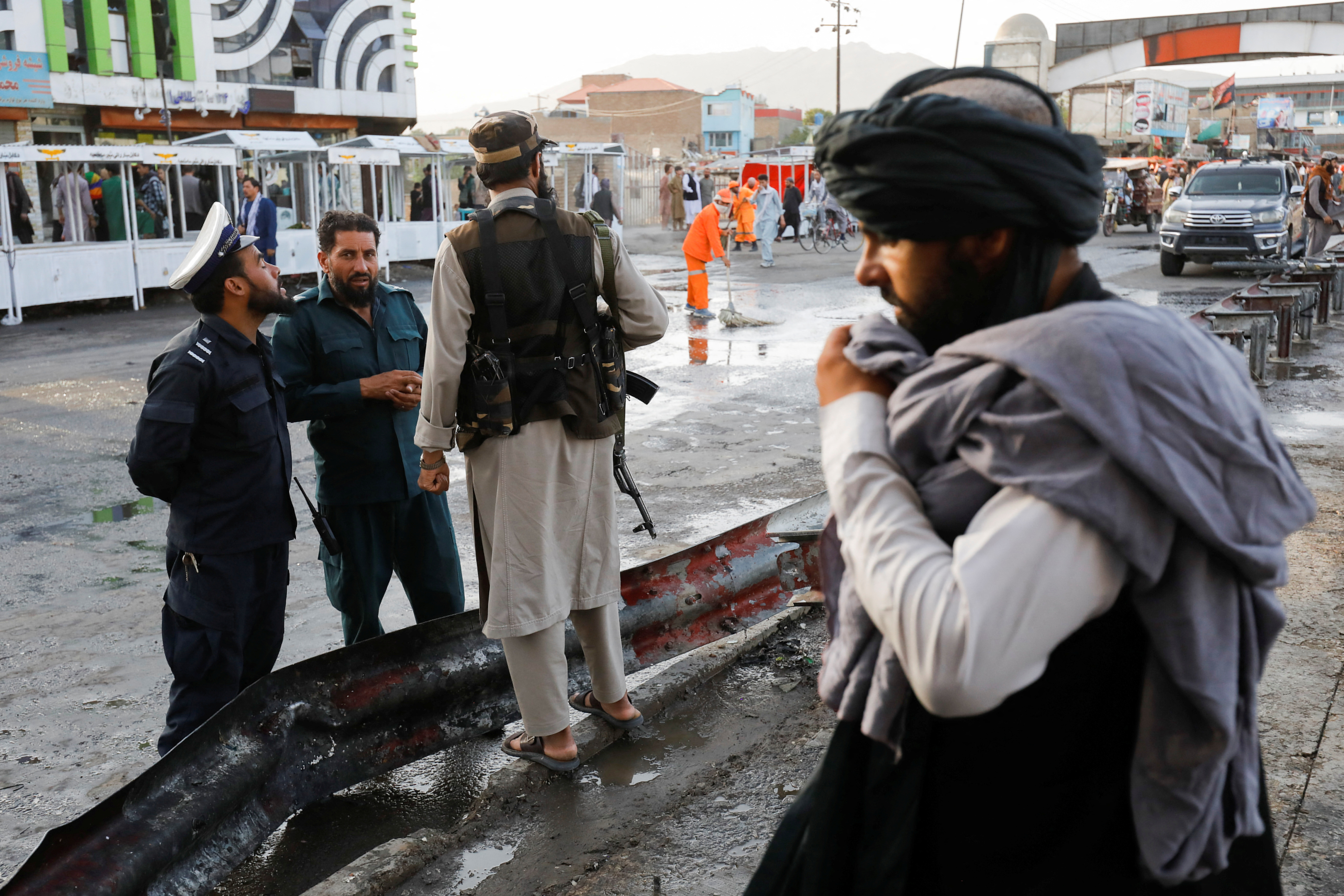 Taliban fighters stand guard at the site of a blast in Kabul