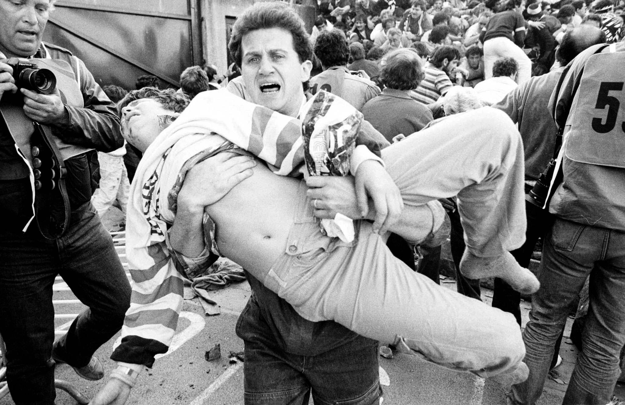INJURED SOCCER FAN IS CARRIED AFTER HEYSEL STADIUM DISASTER.