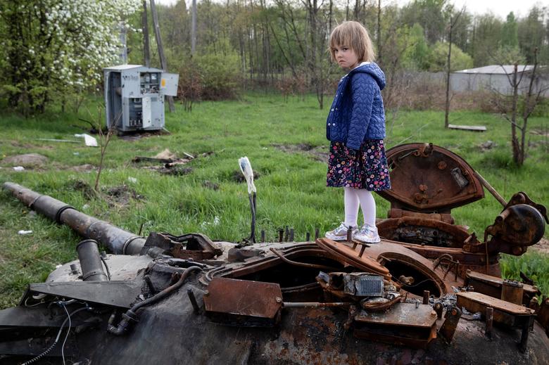 Dijete stoji na uništenom ruskom tenku u blizini Makariva, Kijevska oblast, Ukrajina, 7. maj. REUTERS/Mikhail Palinchak