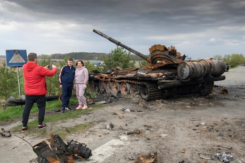 Ljudi poziraju za sliku ispred ruševina ruske vojne mašinerije uništene u selu Rusaniv, Kijevska oblast, Ukrajina, 25. aprila. REUTERS/Vladyslav Musiienko