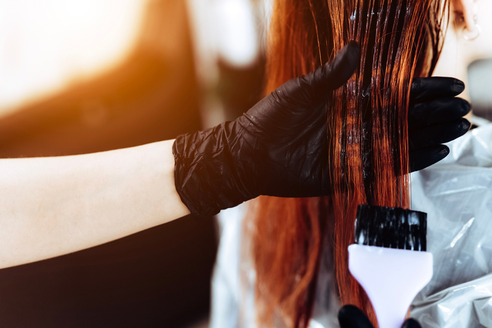 Hairdresser,Applies,A,Redhead,Hair,Mask,To,The,Woman,In