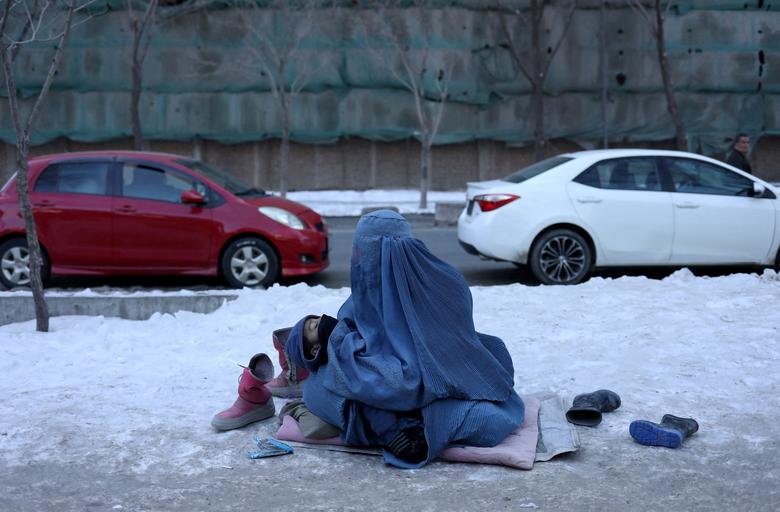 Afganistanka drži svoje dijete i prosi na snijegom prekrivenom trotoaru u Kabulu, Afganistan, 27. januara 2022. REUTERS/Ali Khara