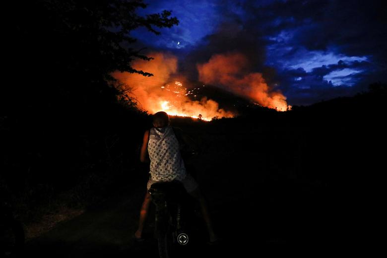 Čovjek koji vozi motor pored požara u Bušatu, Skadar, Albanija 3. august. REUTERS/Florion Goga
