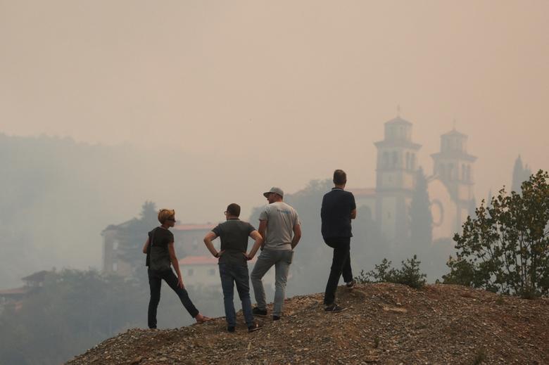 Ljudi gledaju na dvorac Miren prekriven dimom od šumskog požara u blizini granice sa Italijom, u Mirenu, Slovenija, 20. jul. REUTERS/Borut Živulović
