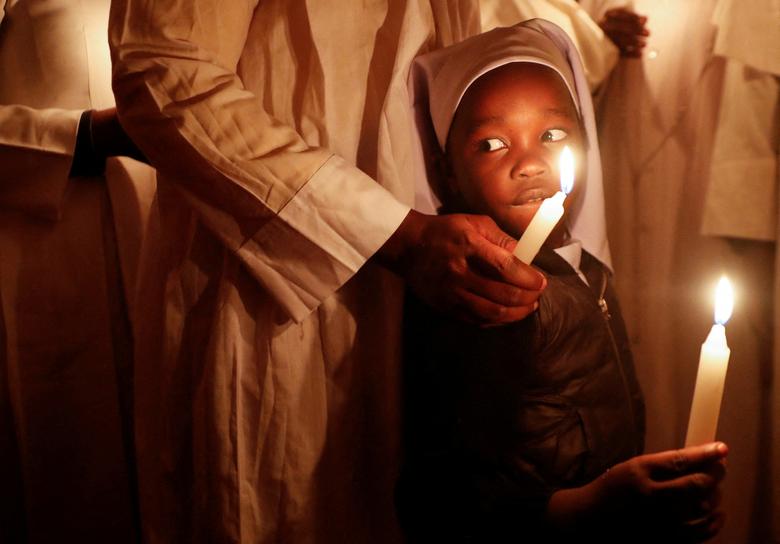 Vjernica vodi svoje dijete nakon što je zapalila svijeću tokom molitve uskršnjeg bdijenja u okrugu Kibera u Nairobiju, Kenija, 17. aprila. REUTERS/Thomas Mukoya
