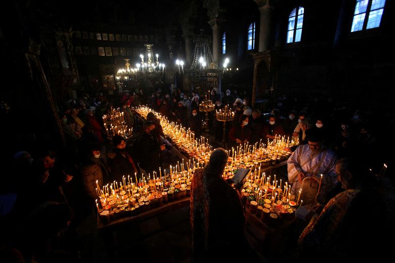 Vjernici se okupljaju oko svijeća zalijepljenih u tegle sa medom tokom mise povodom obilježavanja dana Svetog Haralampija, pravoslavnog zaštitnika pčelara, u crkvi Vavedenja Presvete Bogorodice u Blagoevgradu, Bugarska, 10. februara. REUTERS/Stoyan. Nenov
