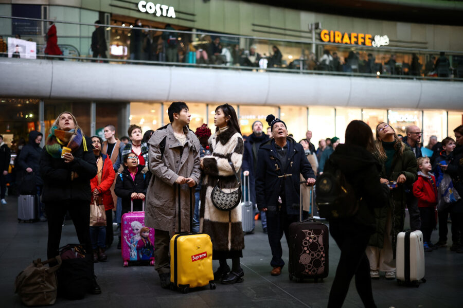 People wait beneath information screens displaying train times at Kings Cross Station, after members of the RMT Union working for Network Rail ended their strike, in London