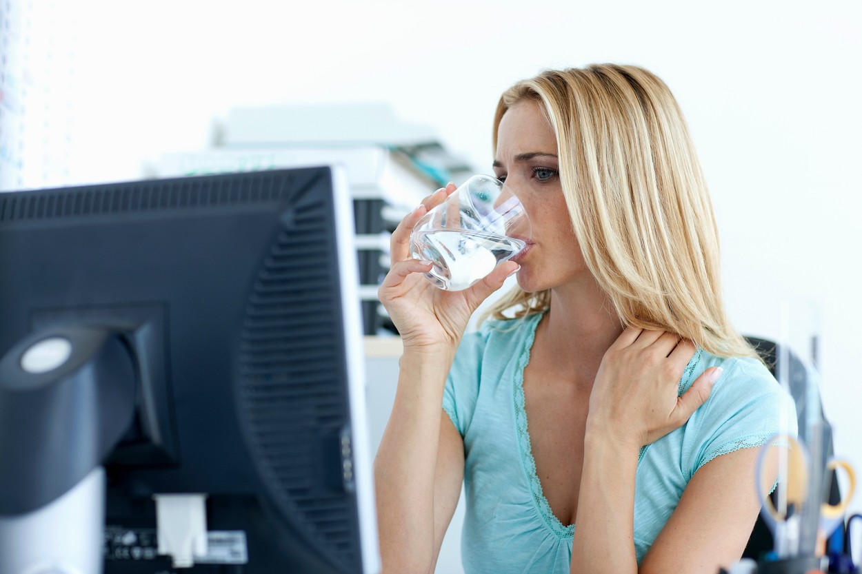 Businesswoman drinking water at desk