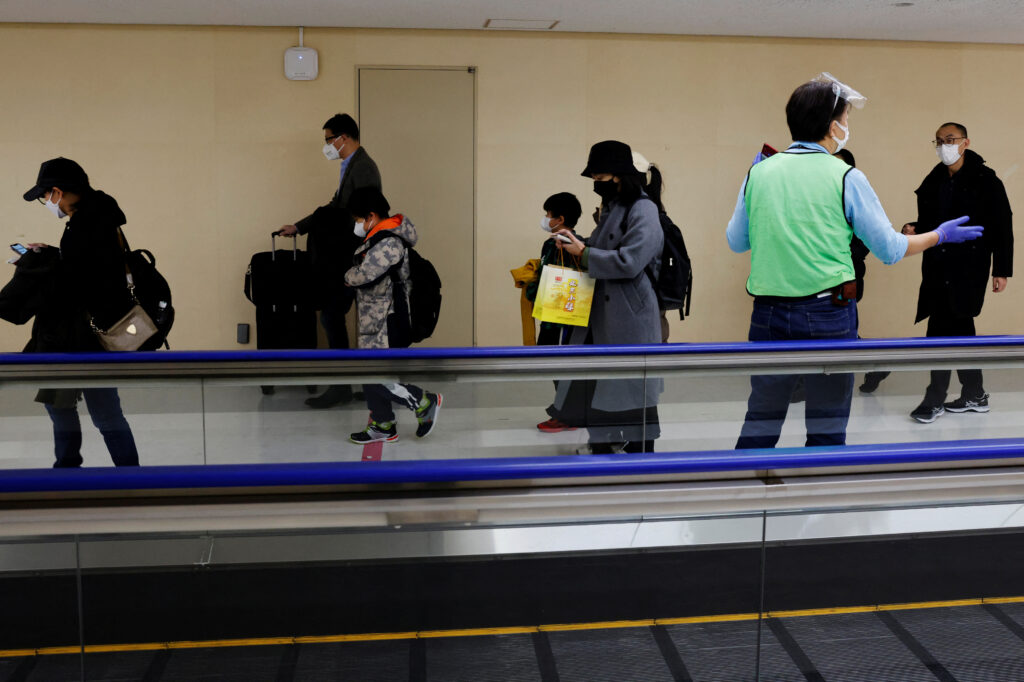 Passengers on a plane from China’s capital Beijing are guided to the coronavirus disease (COVID-19) test area upon their arrival at Narita international airport in Narita