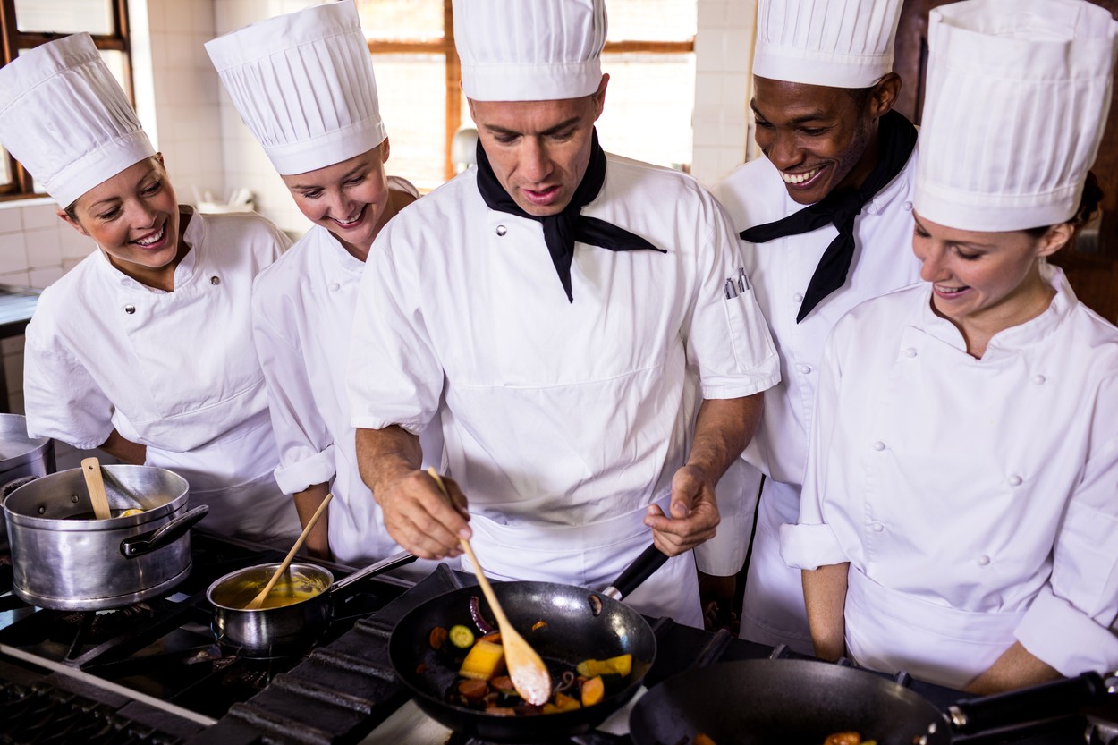 Group of chefs preparing food in kitchen at hotel