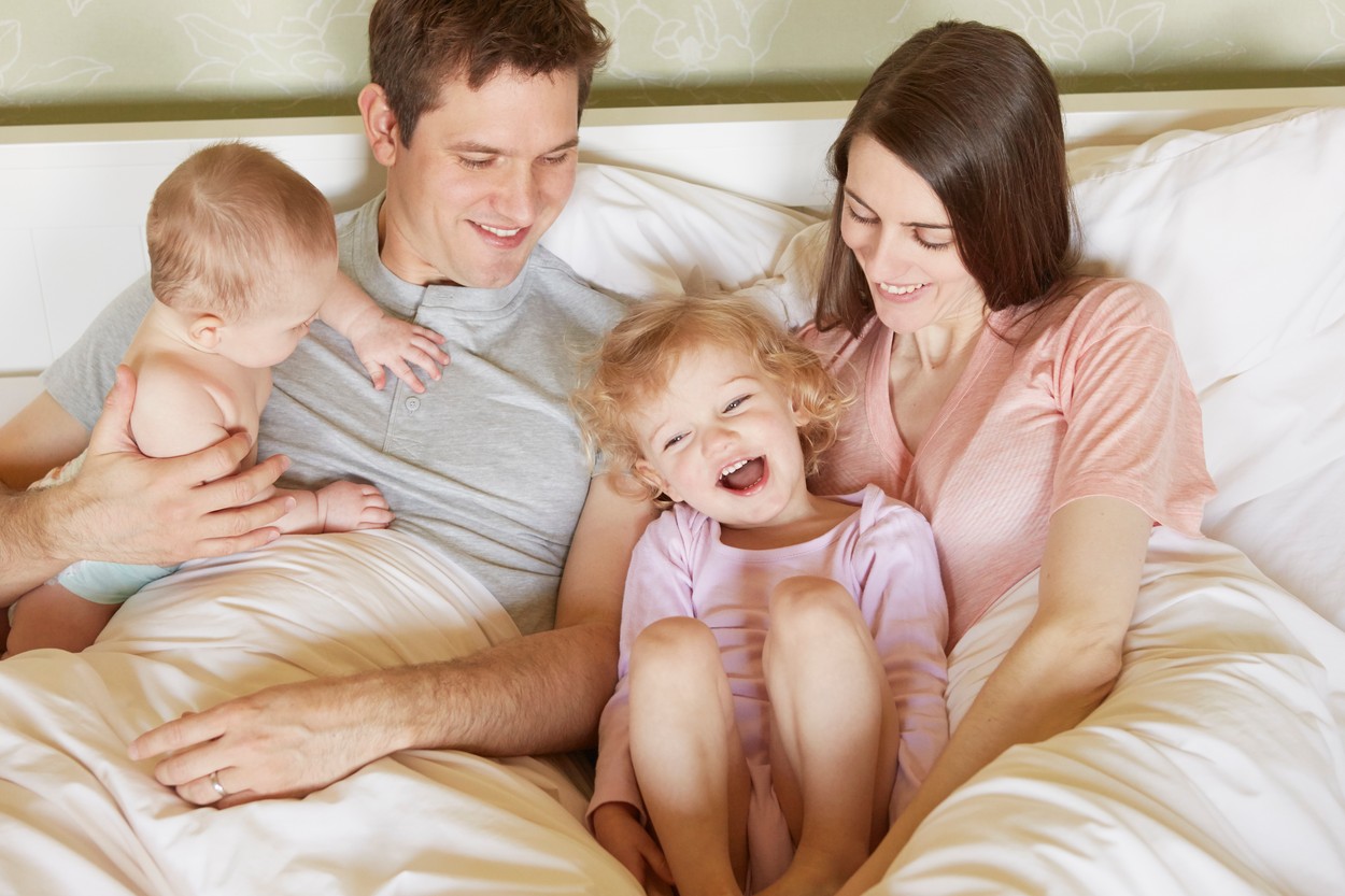 Female toddler and baby sister in bed with parents