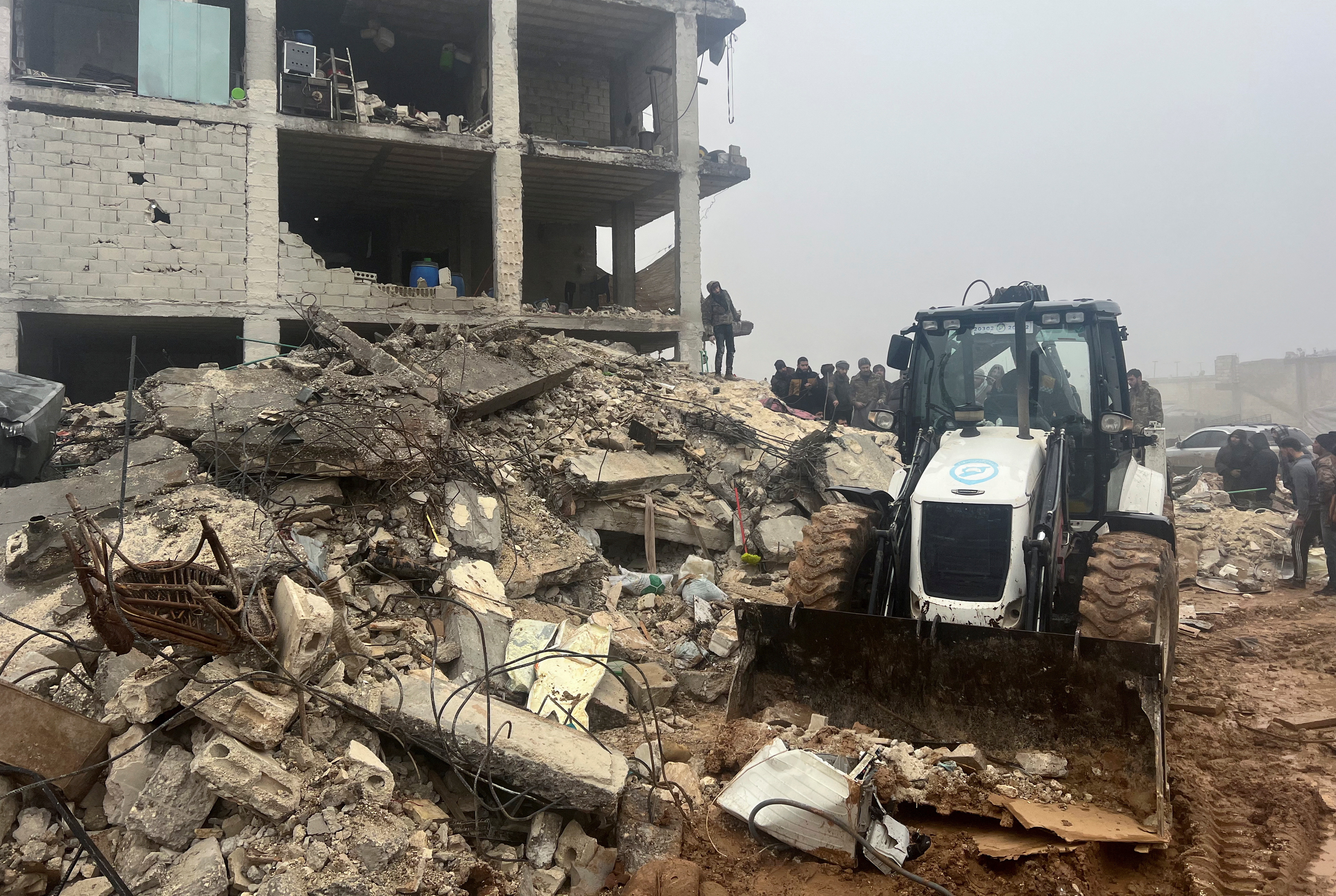 A front loader operates at the site of a damaged building, following an earthquake, in rebel-held town of Jandaris