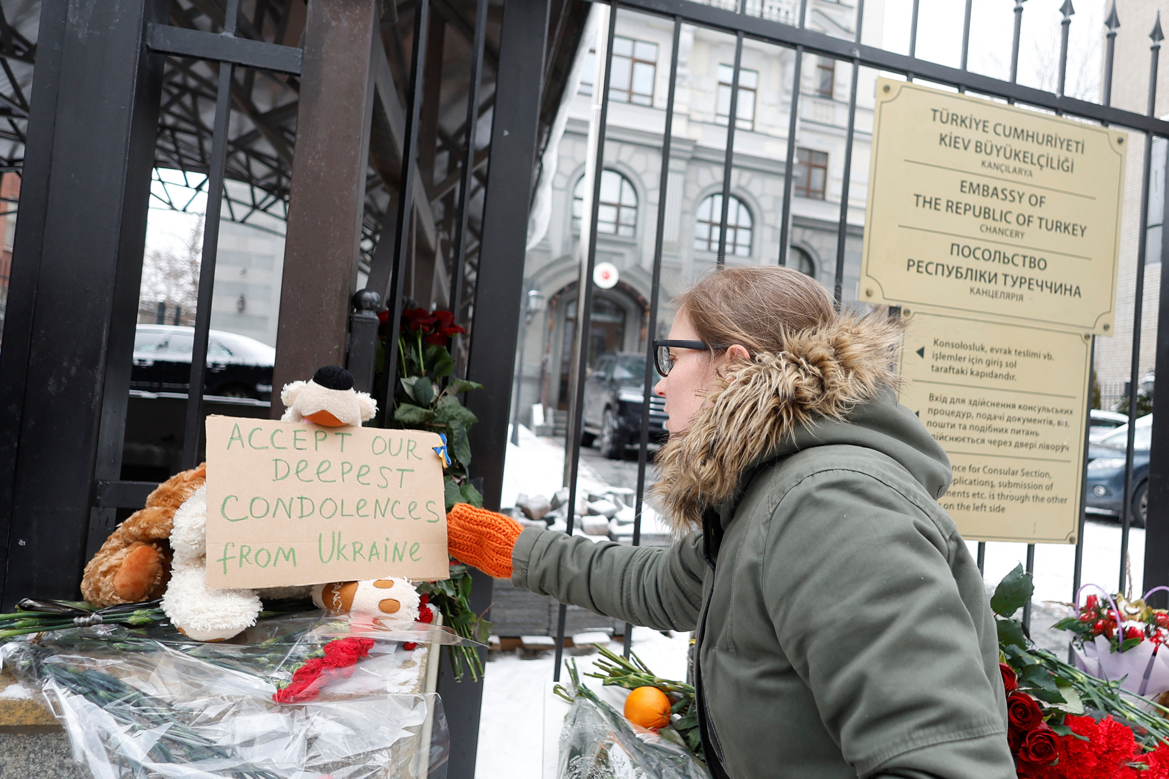 Woman places a board with condolences for the victims of an earthquake in Turkey and Syria, outside of the Turkish embassy in Kyiv