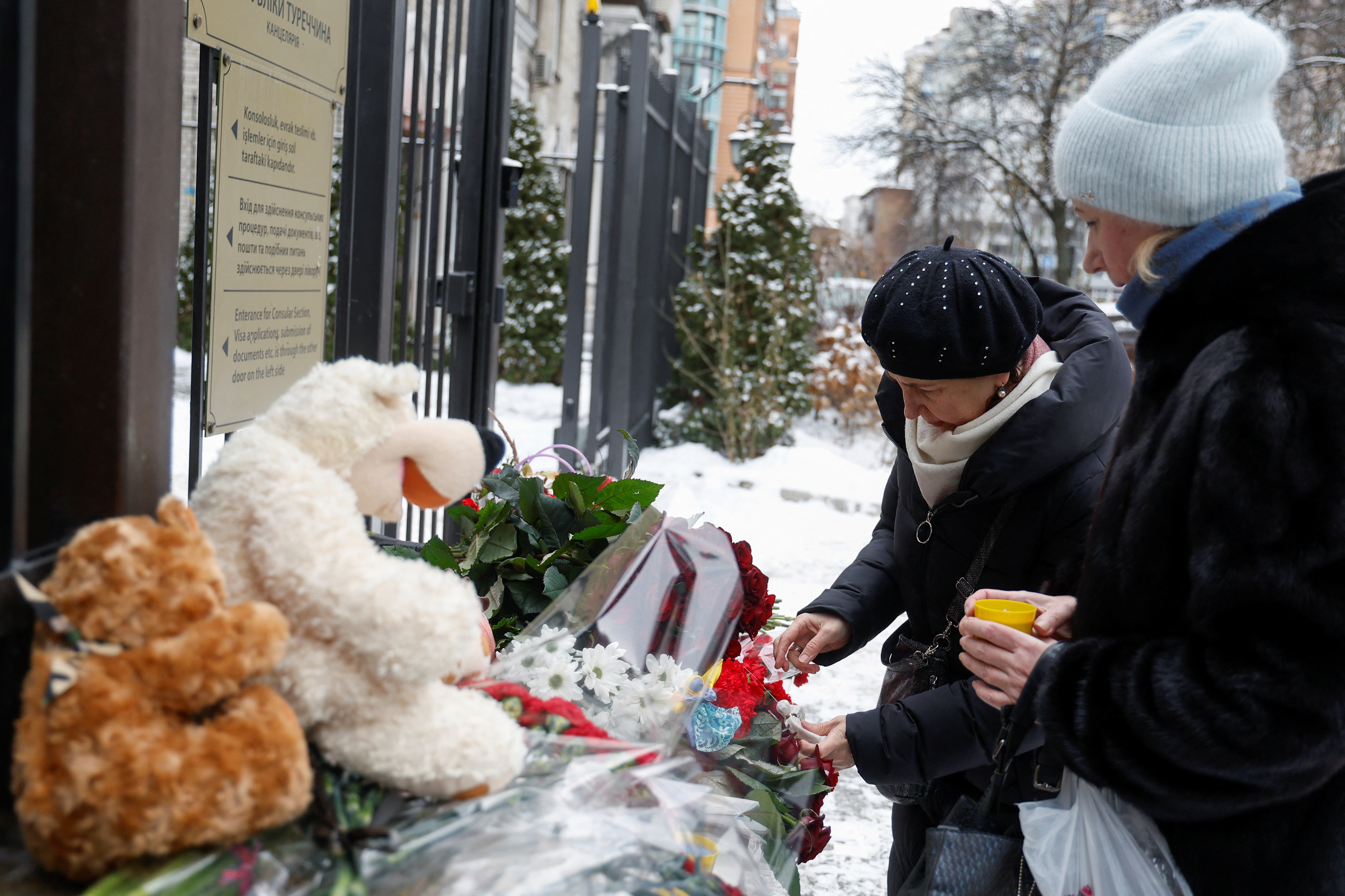 Women place candles and angels figurines to pay tribute to the victims of an earthquake in Turkey and Syria, outside of the Turkish embassy in Kyiv