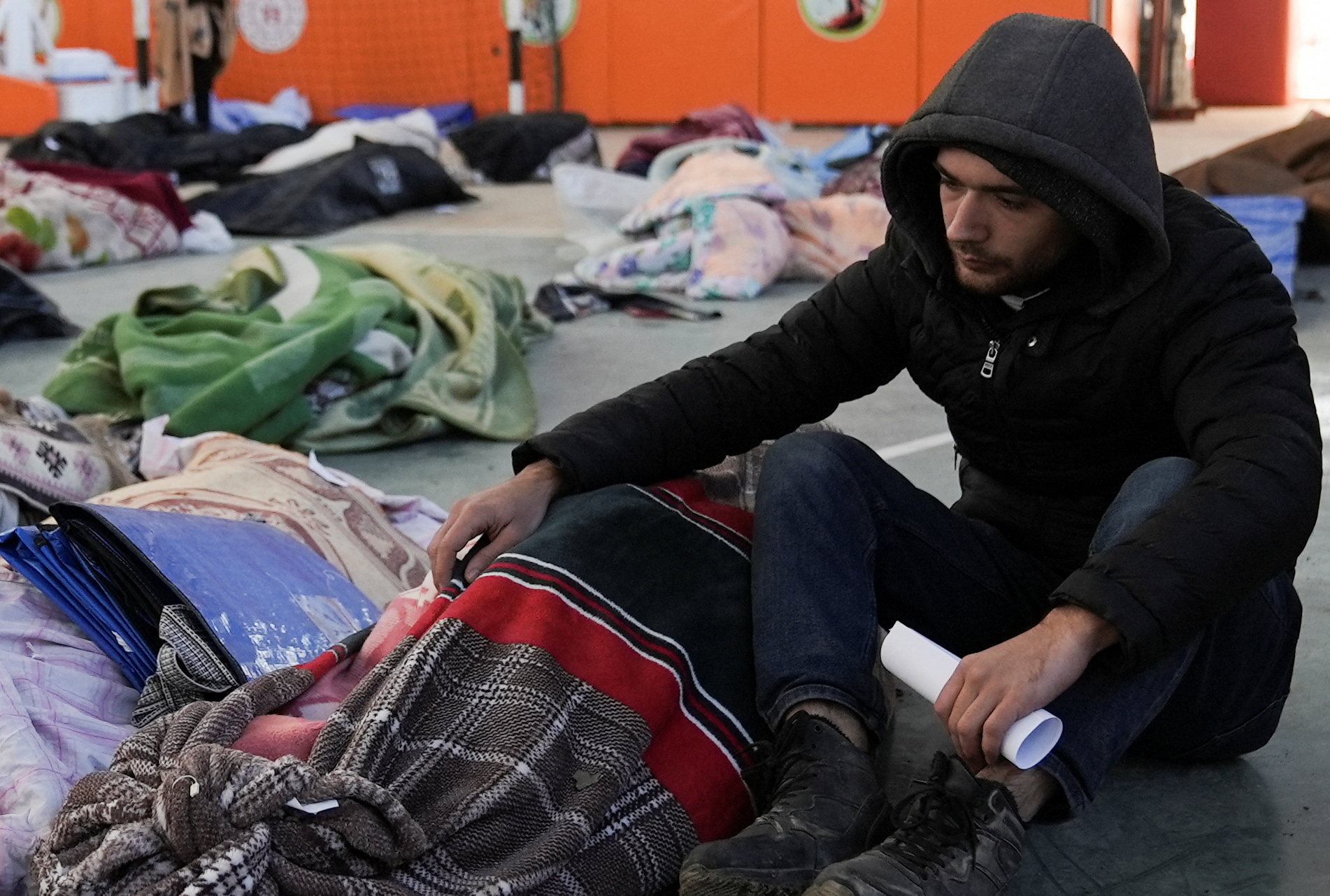 Yunus Emre Kaya sits next to the body of his fiancee Gulcin in a sports hall where relatives are identifying their loved ones in the aftermath of a deadly earthquake in Kahramanmaras