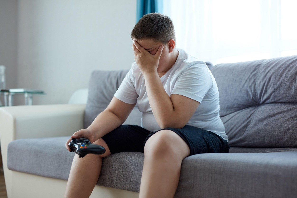 sad fat boy is upset after losing a video game, sit closing face, alone at home