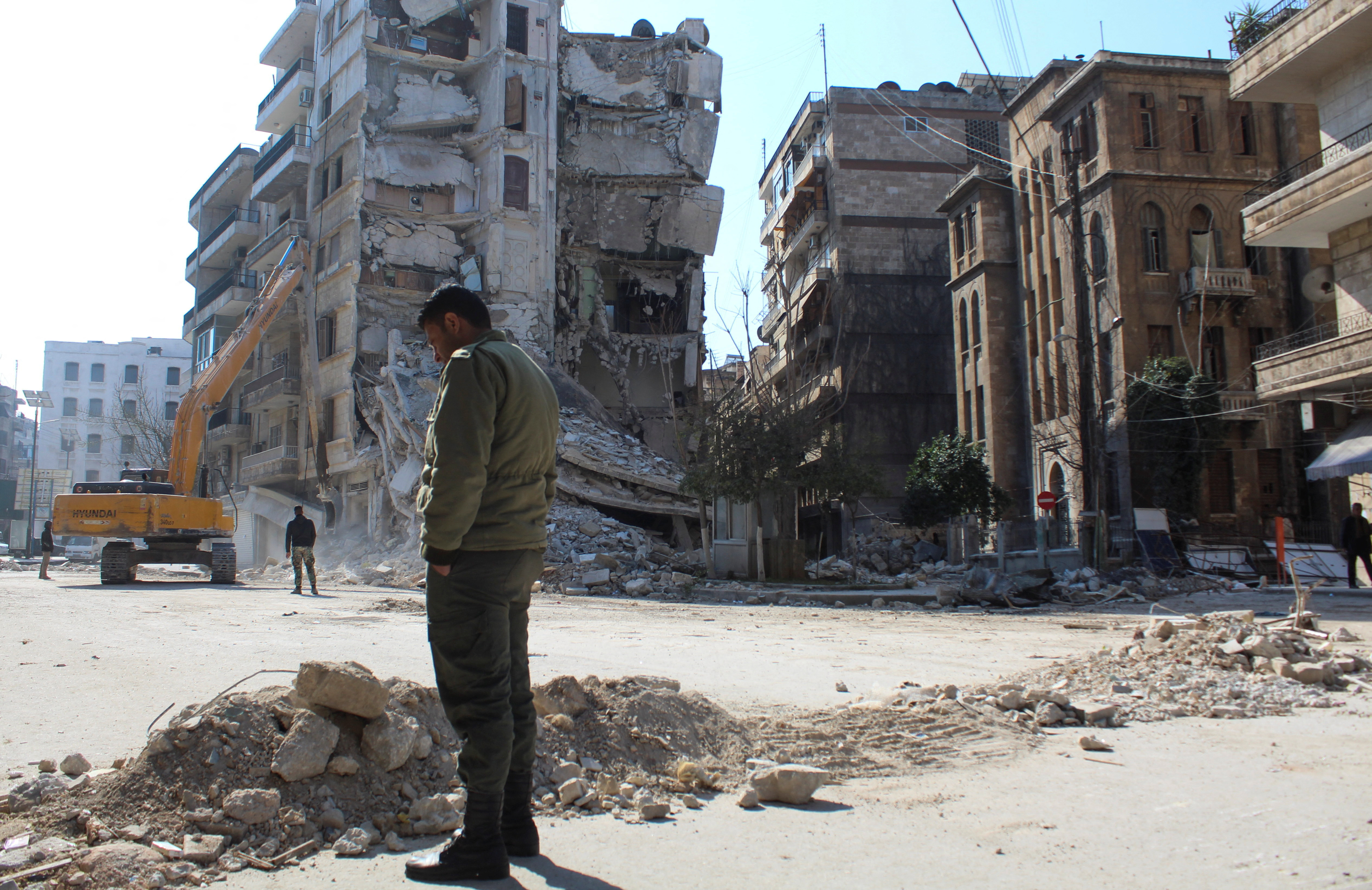 A man stands near damaged buildings, in the aftermath of a deadly earthquake, in Aleppo