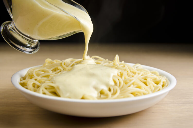 Pouring,White,Sauce,Over,Plate,Of,Cooked,Spaghetti