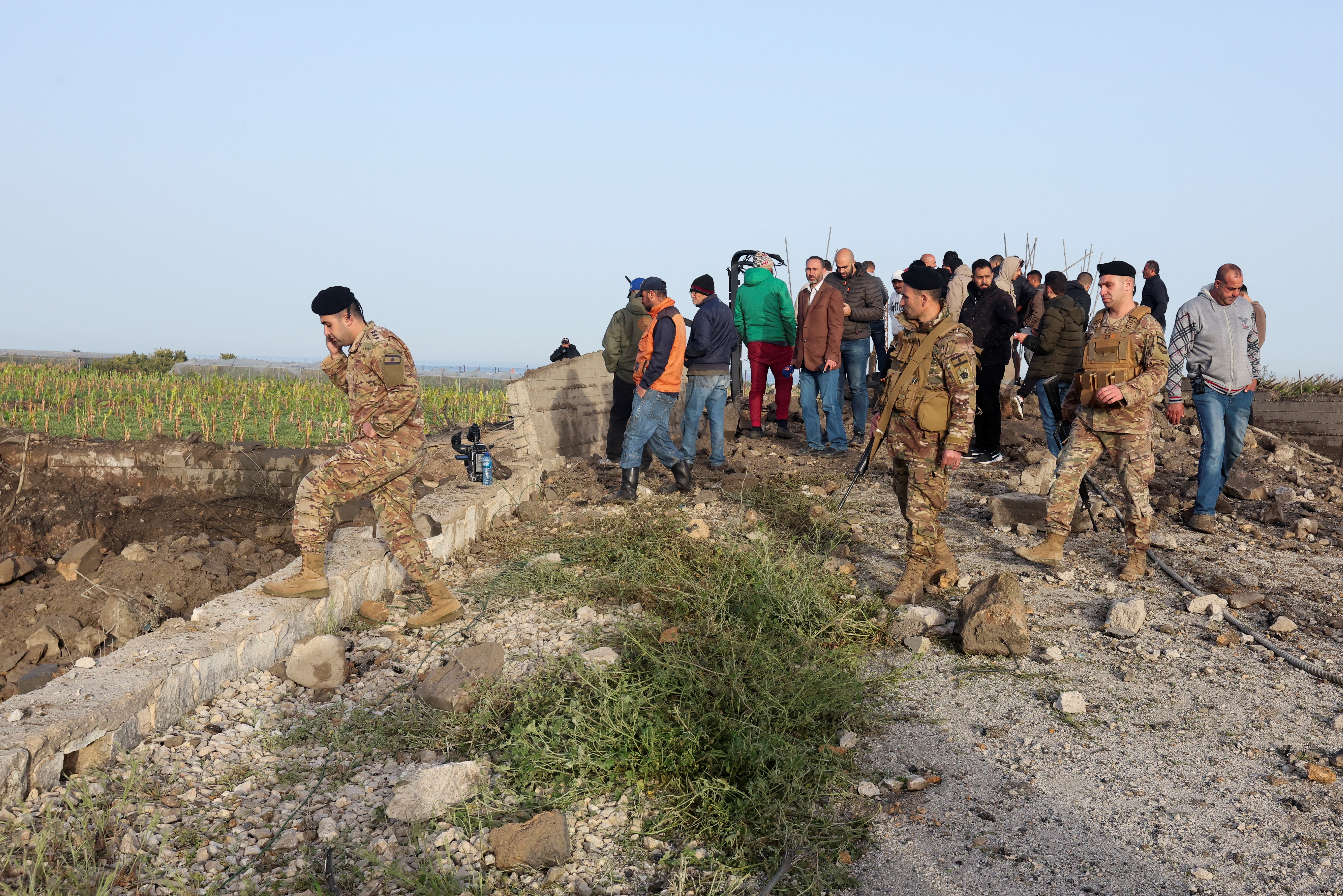 Lebanese army soldiers and people inspect the damage following Israeli air strikes, in Ras al-Ain