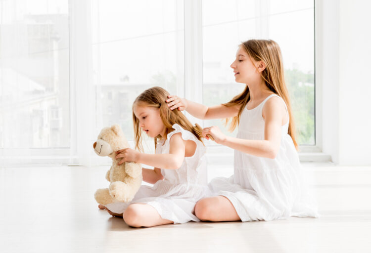 Lovely,Little,Girl,Brushing,Hair,Of,Her,Younger,Sister,While