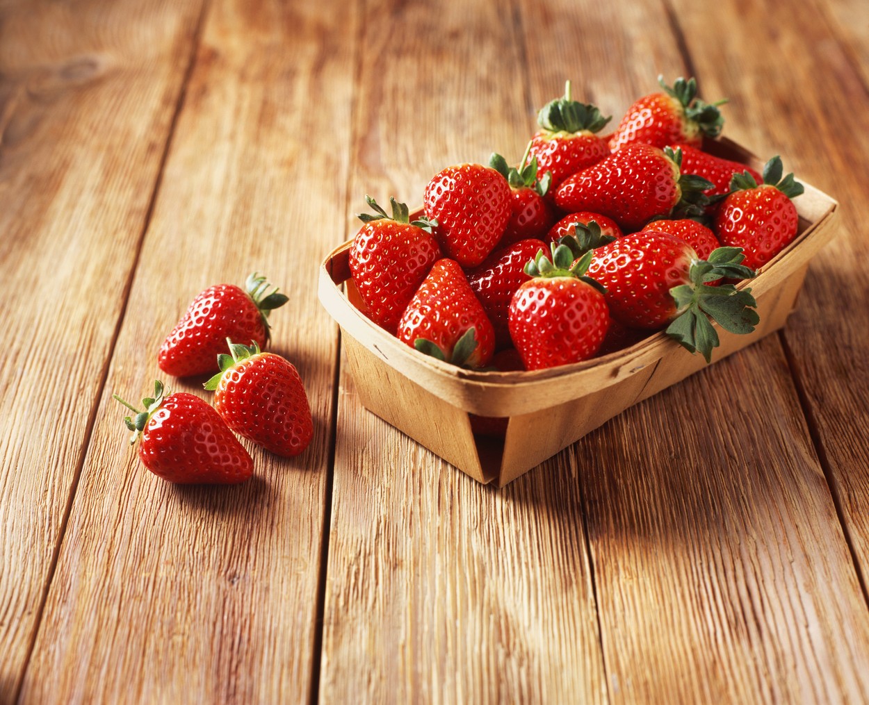Punnet of strawberries on wooden table