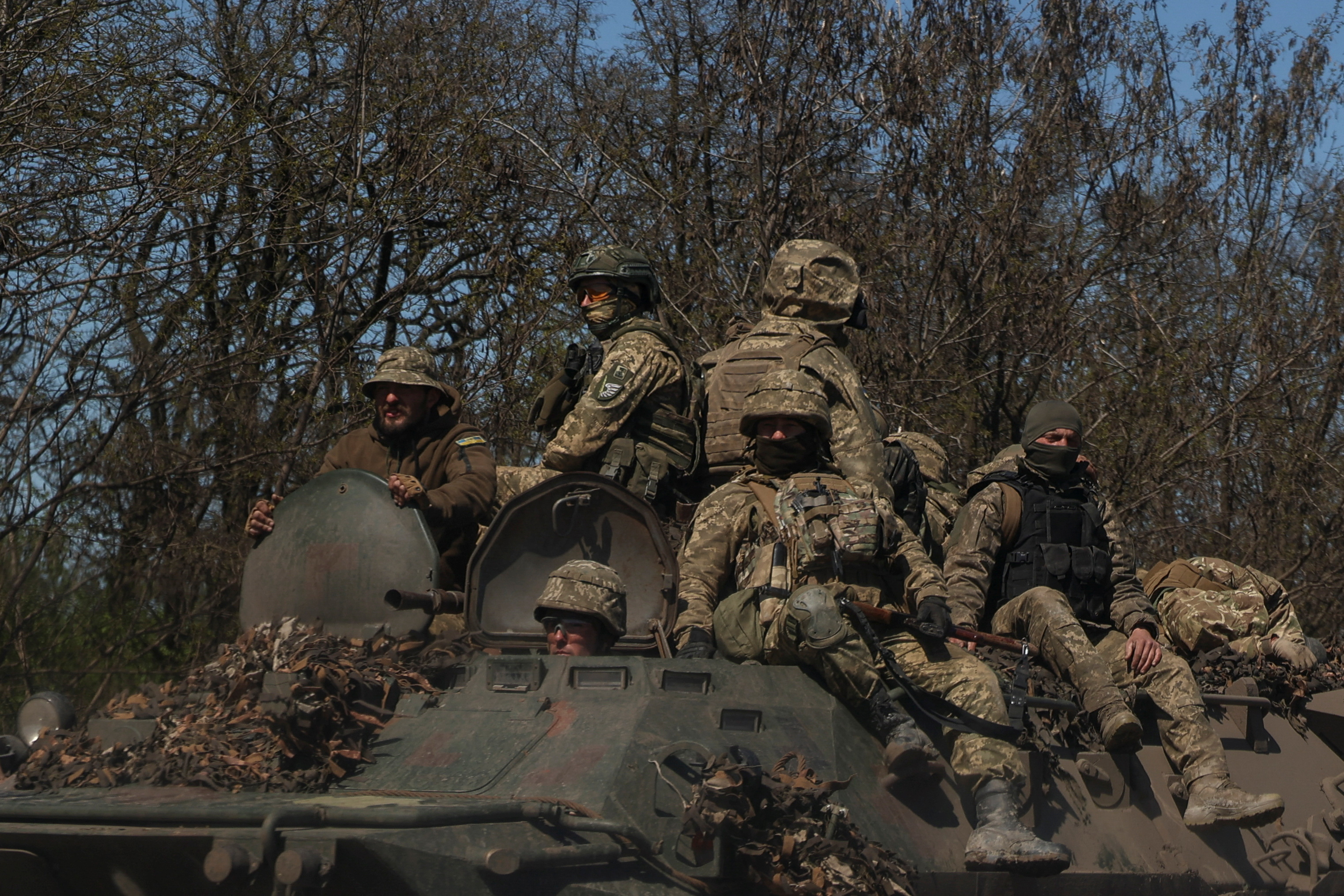 Ukrainian service members ride atop of an armoured personnel carrier near a front line in Donetsk region