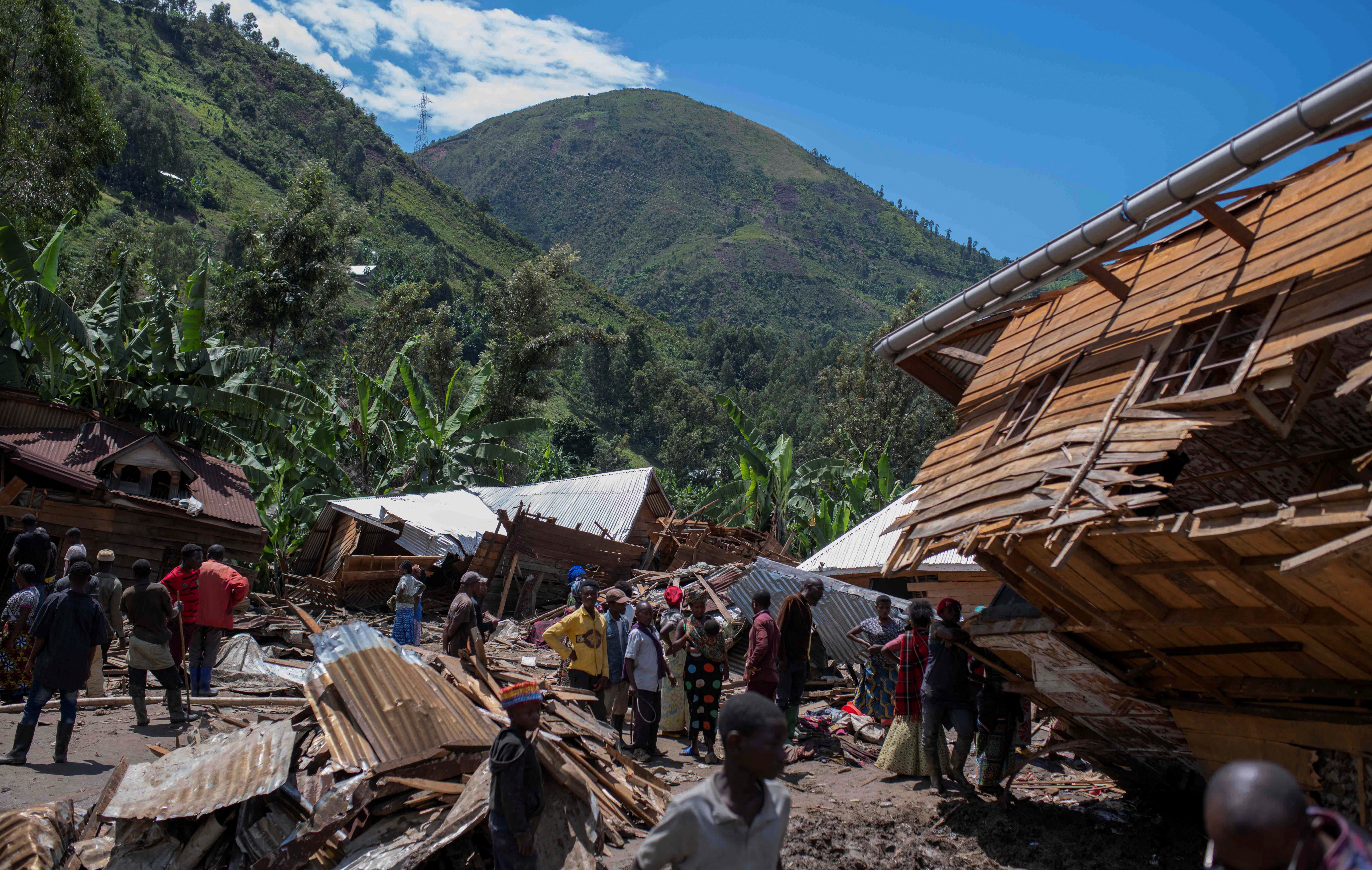 Congolese civilians gather after the death of their family members following rains that destroyed buildings and forced aid workers to gather mud-clad corpses into piles in the village of Nyamukubi
