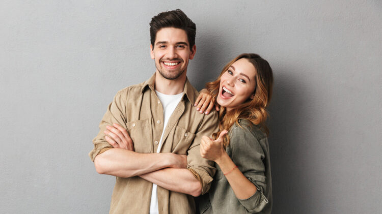Portrait,Of,A,Cheerful,Young,Couple,Standing,Together,Isolated,Over