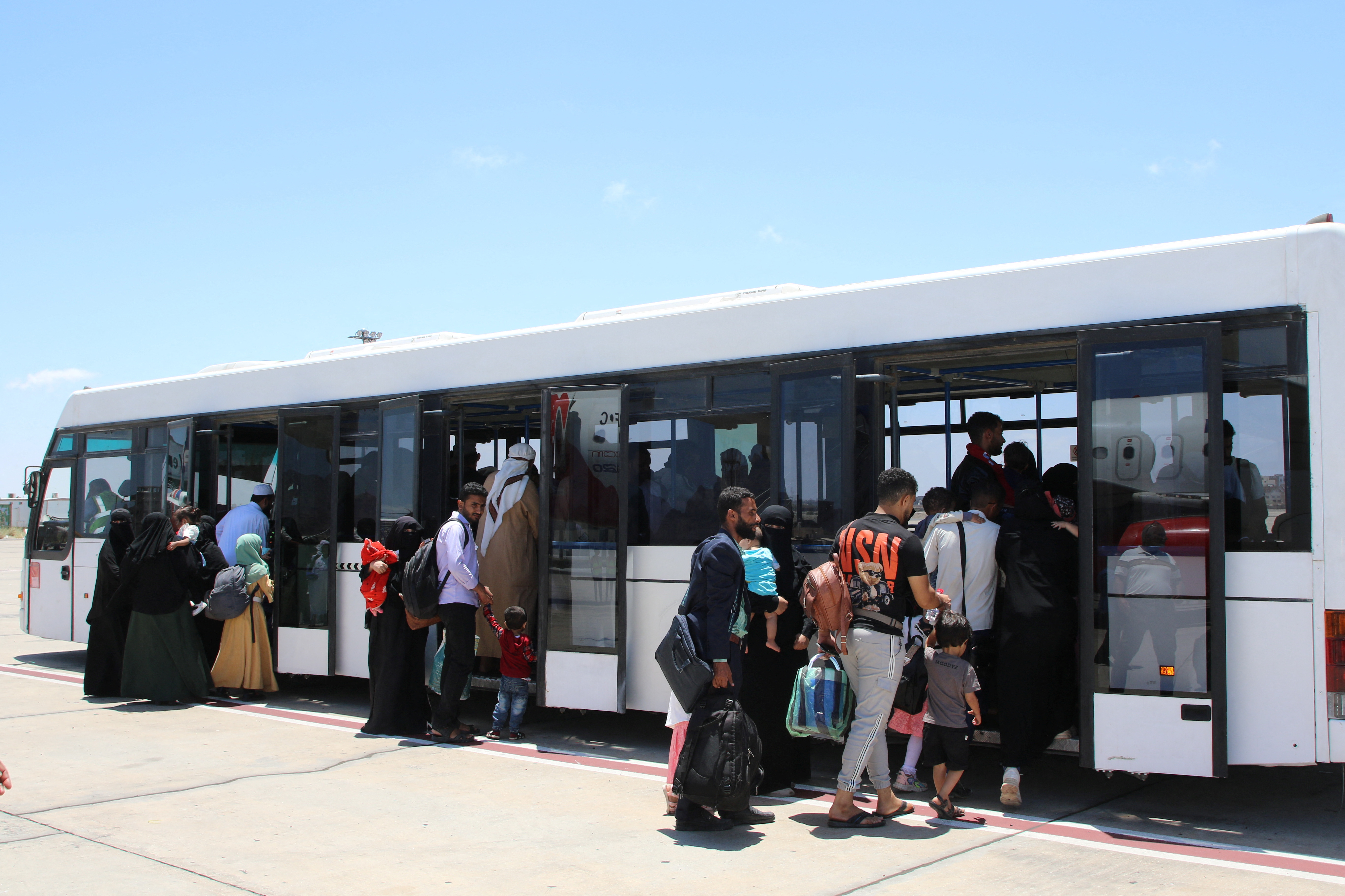 Yemenis evacuated from Sudan board a bus after disembarking a Yemen Airways plane upon arrival at Aden airport in Aden