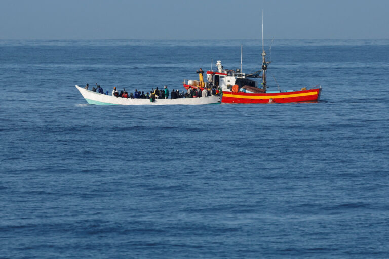 FILE PHOTO: Fishing boat helps a wooden boat with migrants, near the coast on the Bahia Feliz Beach
