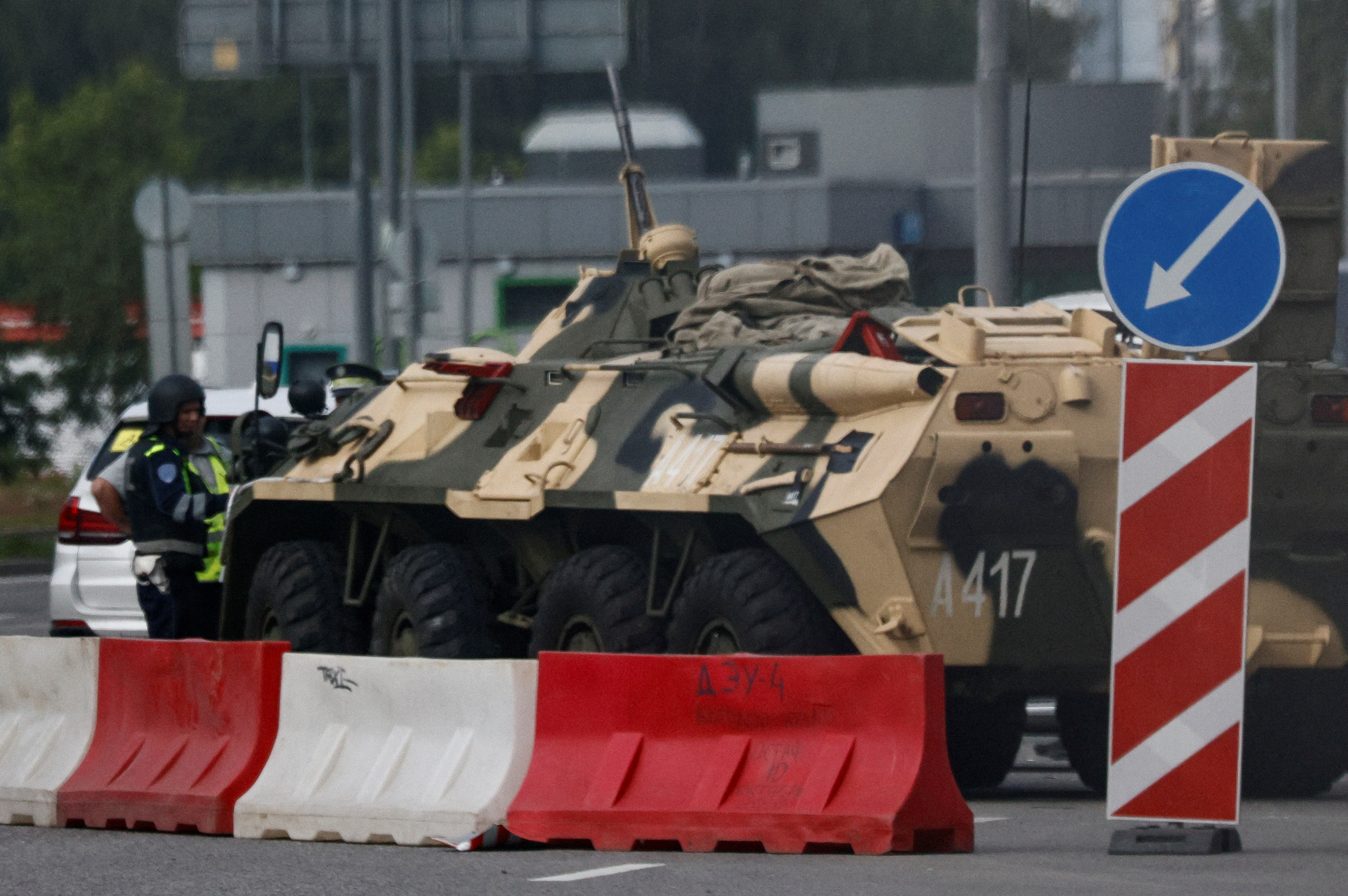 A traffic police officer checks a car next to an armoured personnel carrier (APC) in Moscow