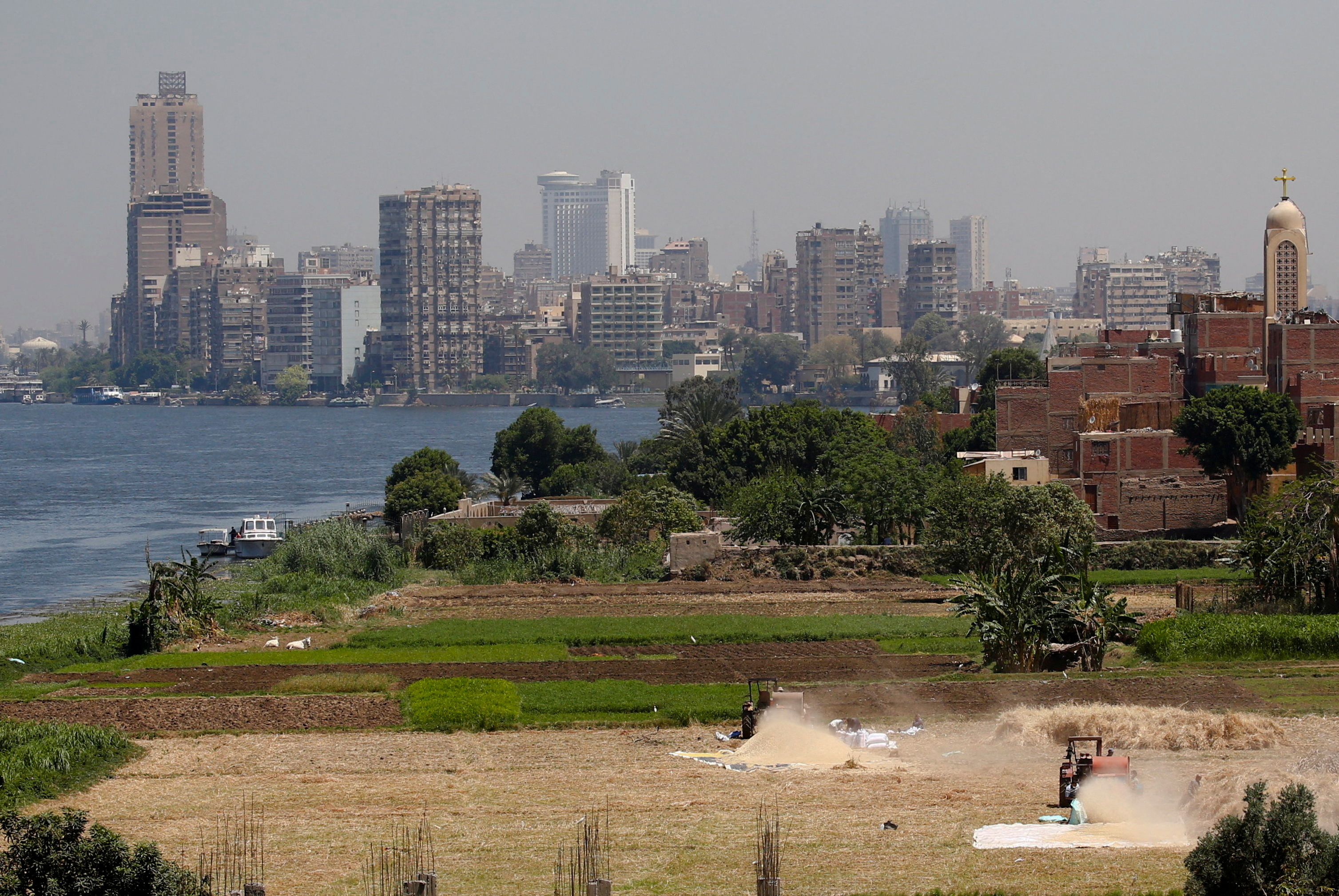 FILE PHOTO: Farmers use a threshing machine as they harvest their wheat crop at a farmland on an island on the River Nile next to the capital city of Cairo