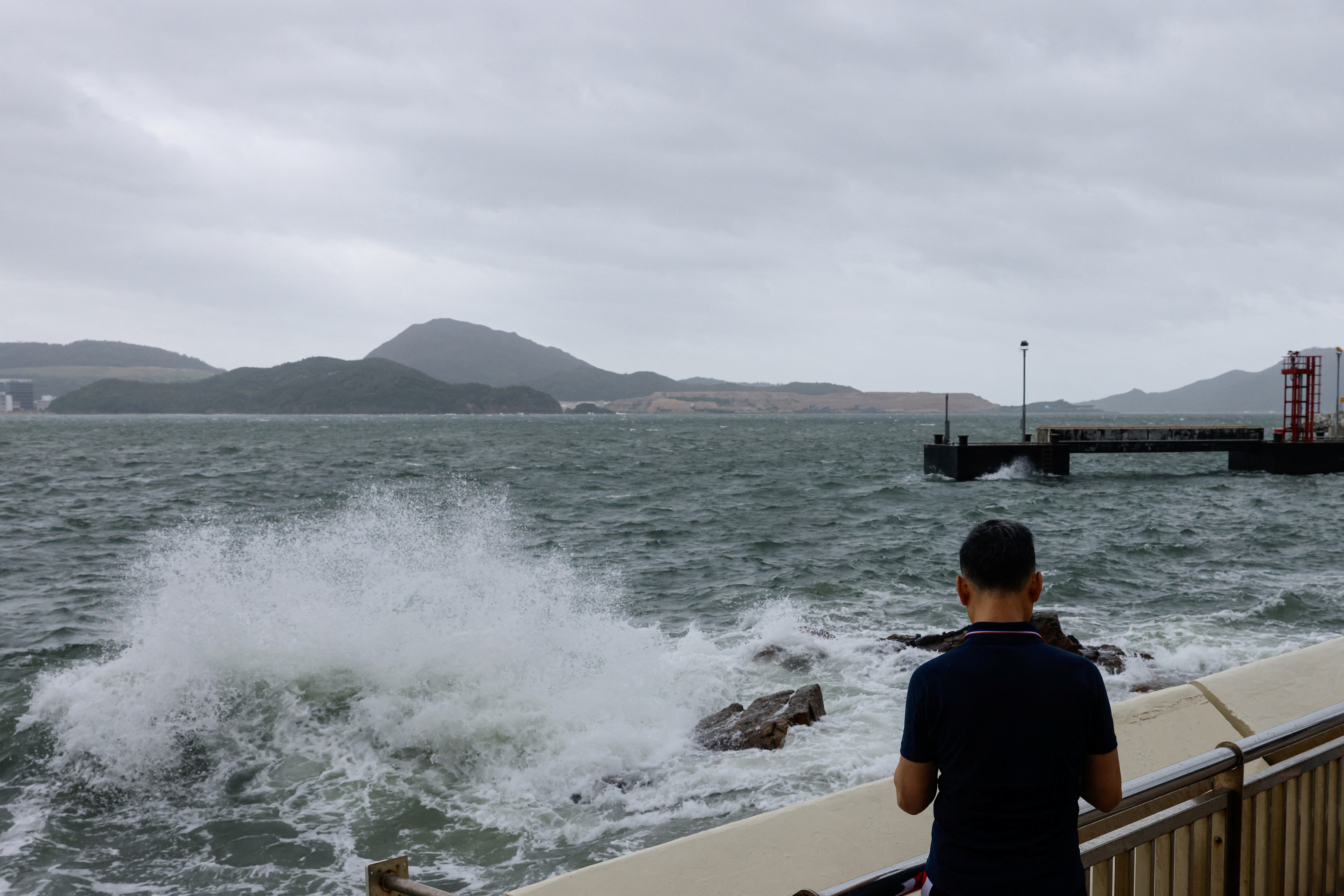 A man watches the waves at the seaside as Typhoon Talim approaches, in Hong Kong
