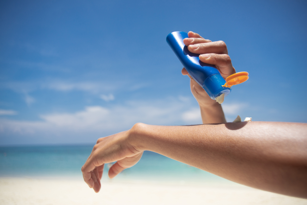 Woman,Applying,Sunscreen,On,Her,Hands,From,A,Bottle,On