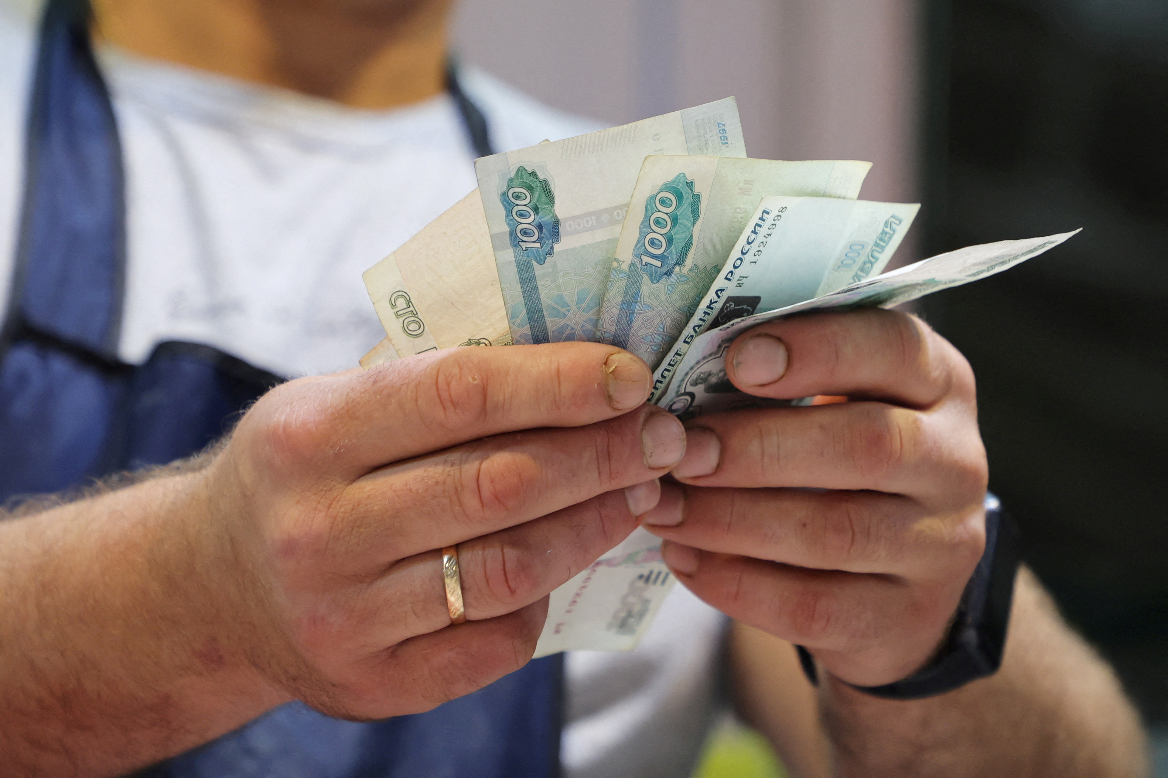 FILE PHOTO: A vendor counts Russian rouble banknotes at a market in Saint Petersburg