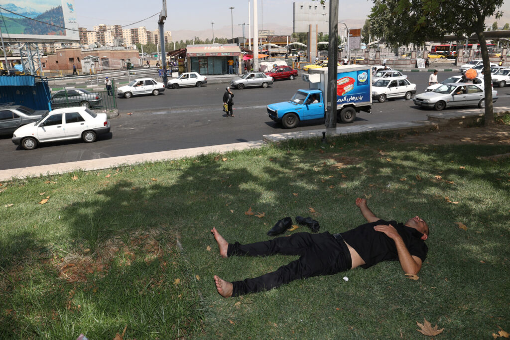 An Iranian man rests in the shade of a tree during the heat surge in Tehran