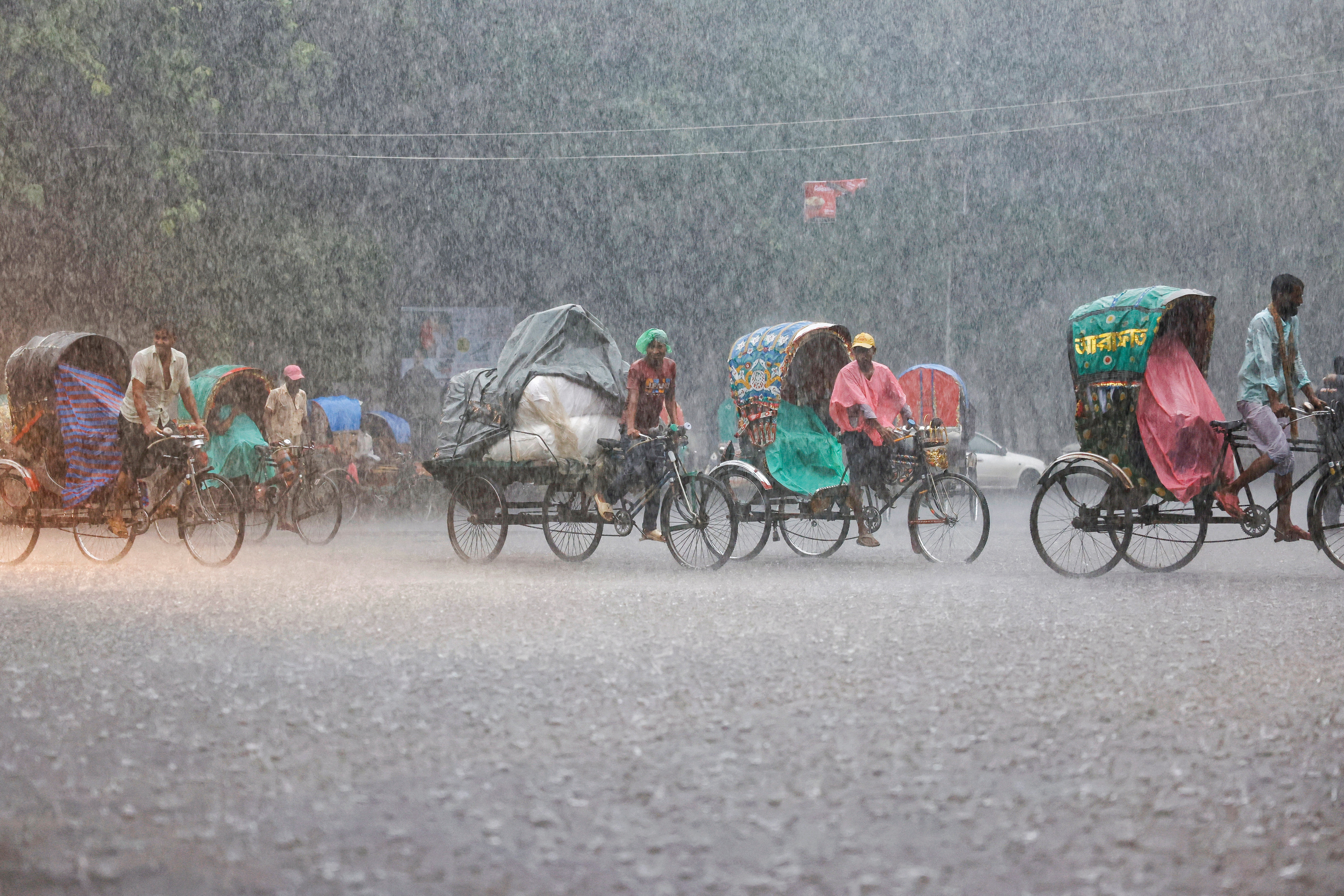 Rickshaws move on the street during continuous rain in Dhaka