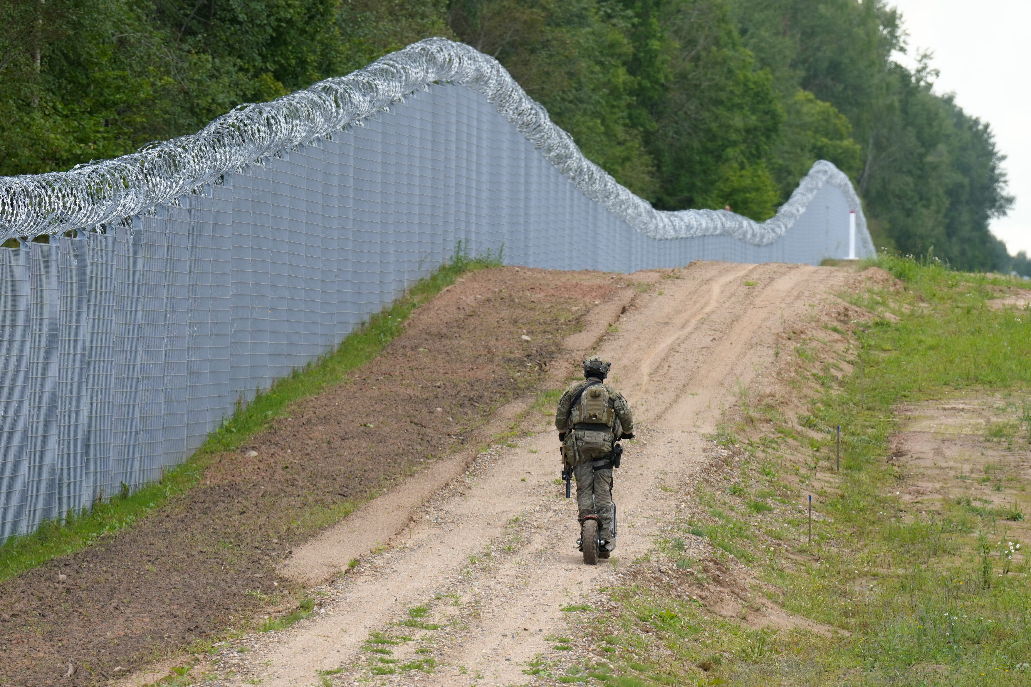 Latvian special unit Border Guard officer patrols along the fence at Latvia-Belarus border near Robeznieki