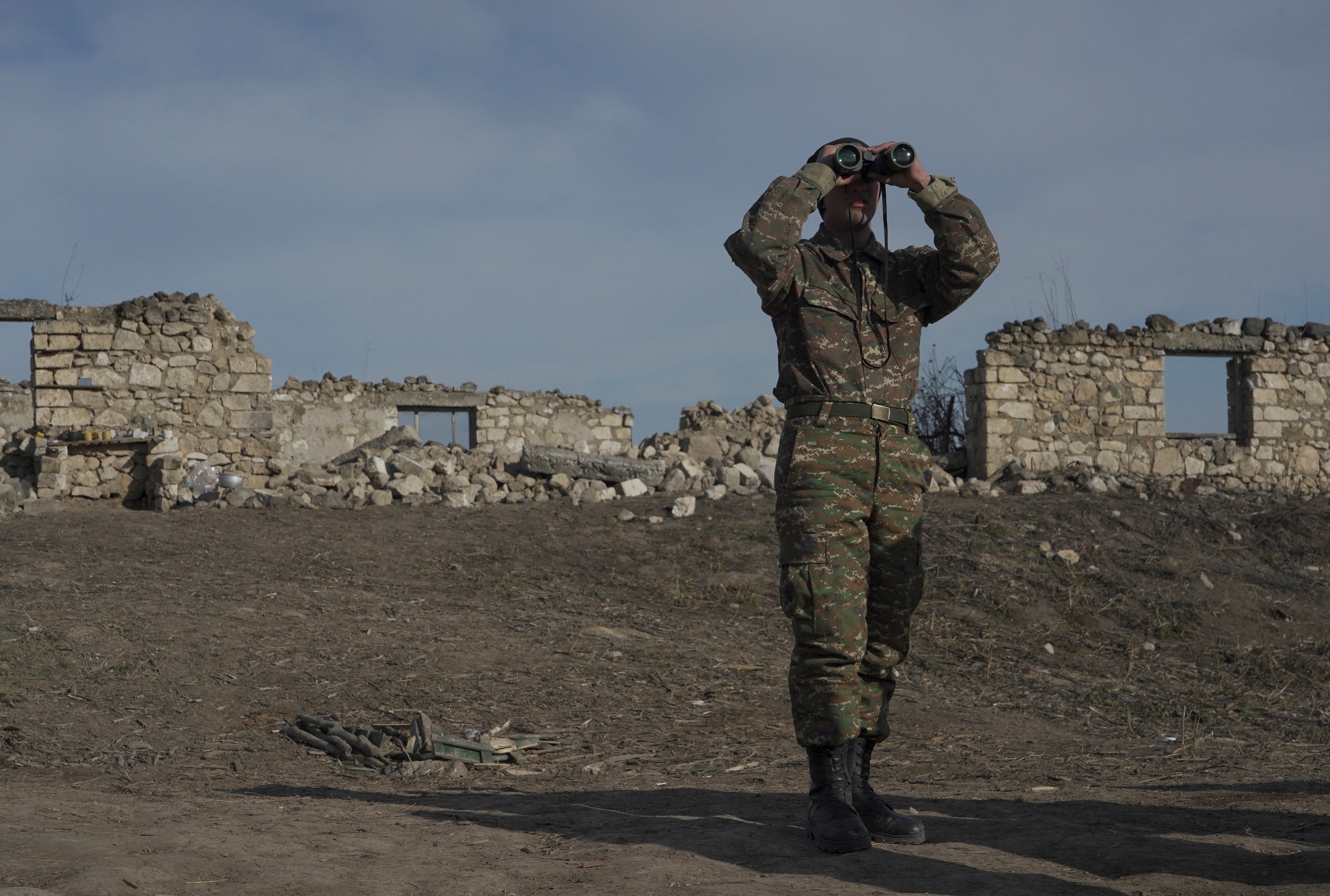 FILE PHOTO: An ethnic Armenian soldier looks through binoculars as he stands at fighting positions near divided Taghavard village in Nagorno-Karabakh region