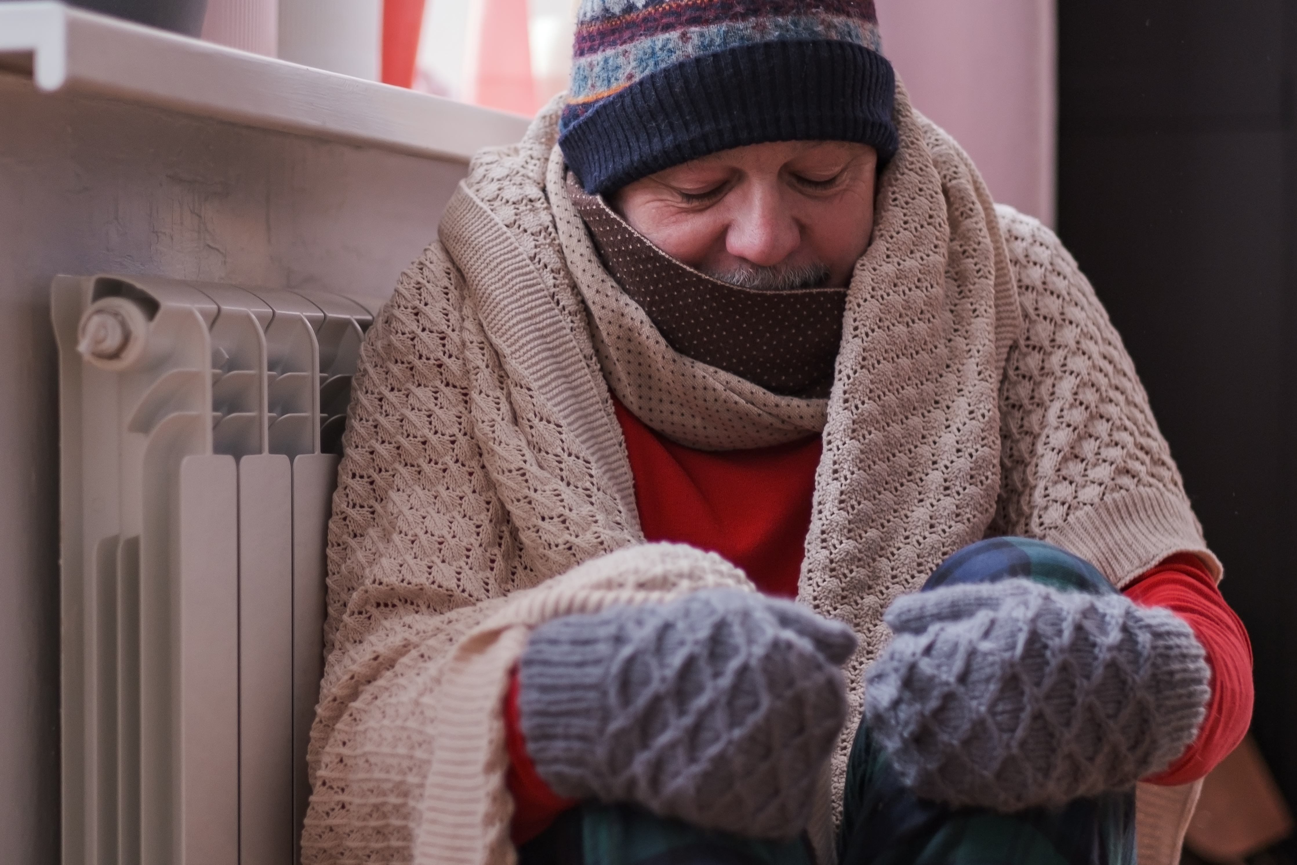 Man feeling cold at home with home heating trouble
