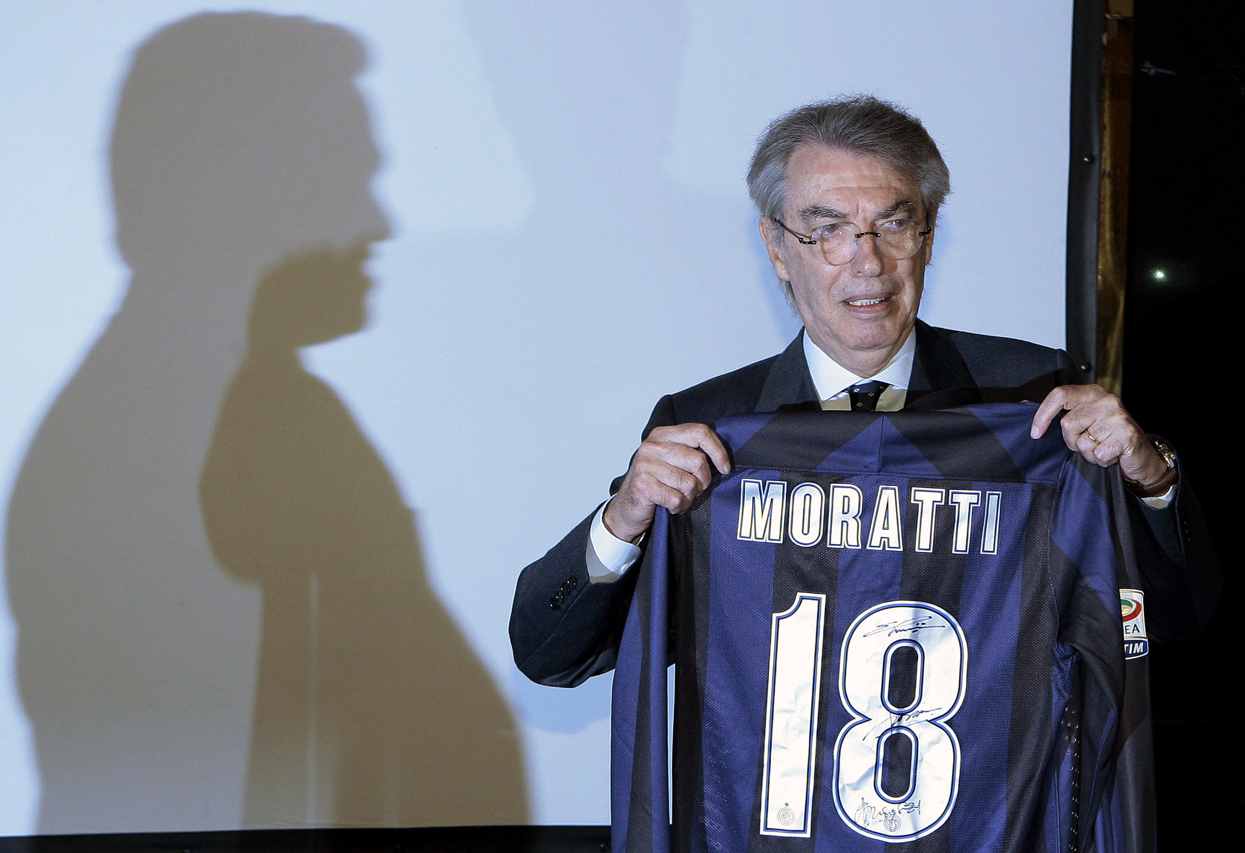 Inter Milan's honorary chairman Moratti holds an Inter Milan jersey as chairman Thohir casts a shadow on the screen before a news conference in Milan