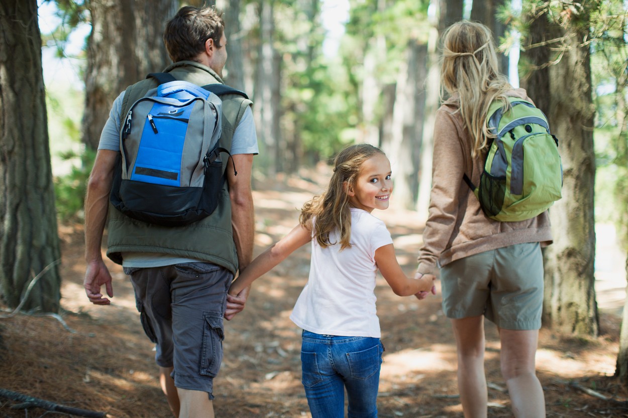 Smiling girl hiking with parents in woods