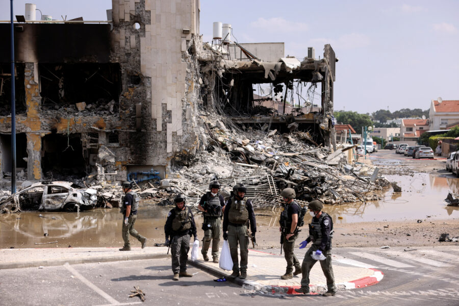 Israeli security gather near a rifle at the site of a battle following a mass infiltration by Hamas gunmen from the Gaza Strip, in Sderot
