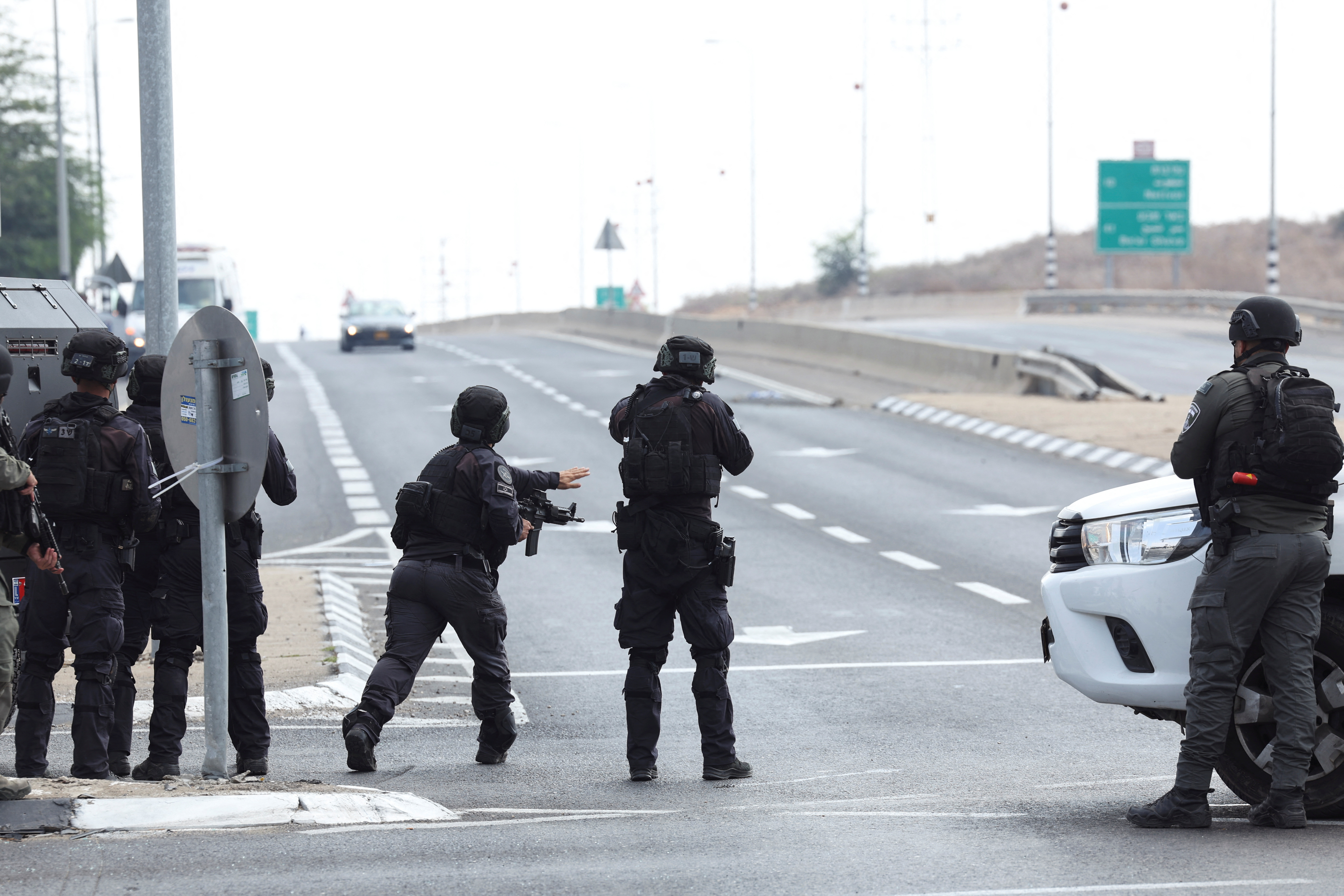 Israeli security take position as a car approaches on a road following a mass infiltration by Hamas gunmen from the Gaza Strip, near Sderot