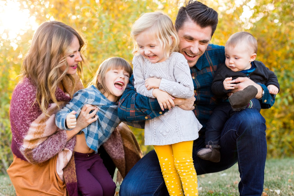 Happy family with tree children (6-11 months, 2-3, 4-5) playing in park
